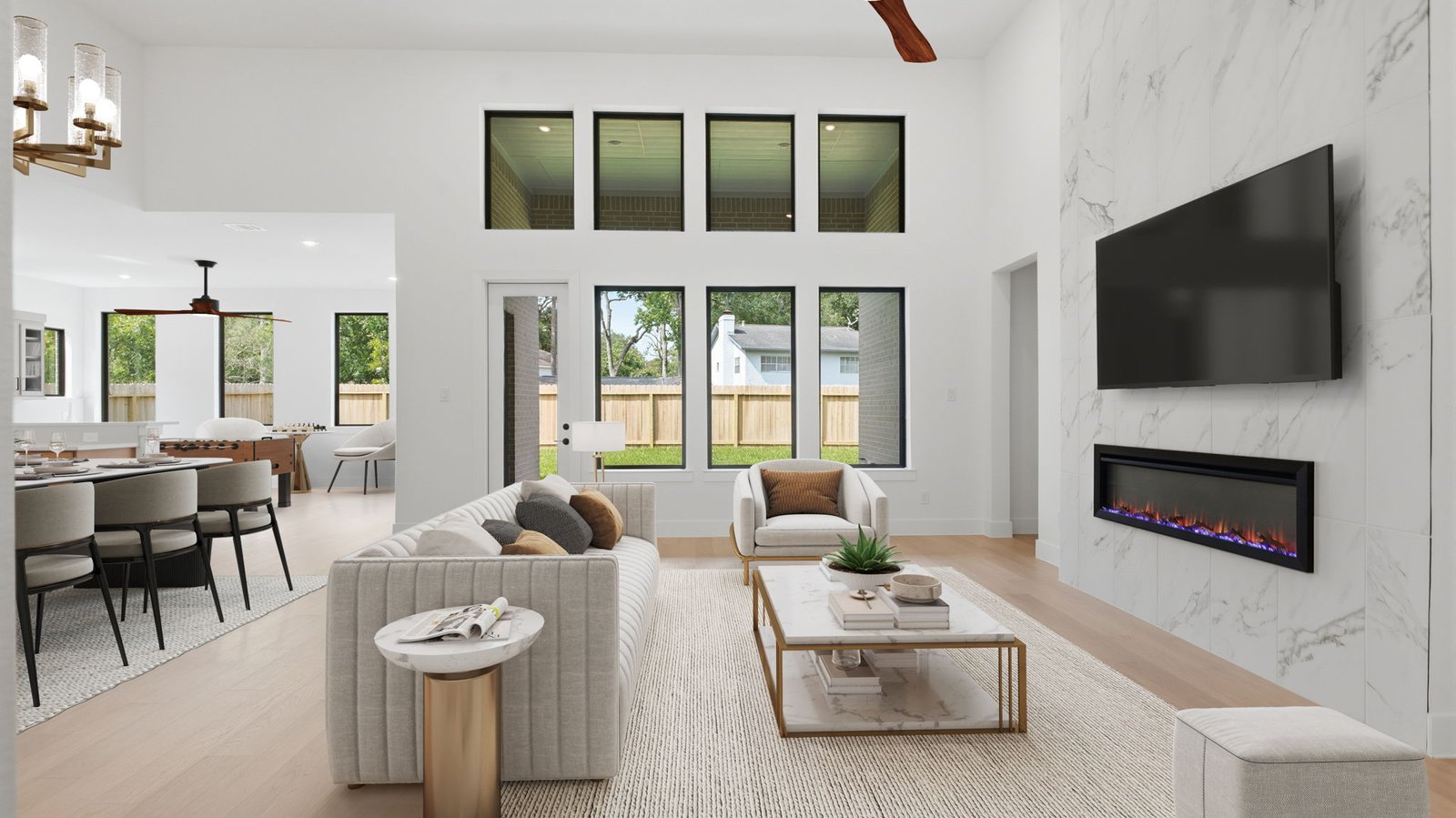 Elegant living room with soaring ceilings, a cozy electric fireplace, open-concept design, and seamless flow into a chef-inspired kitchen.
