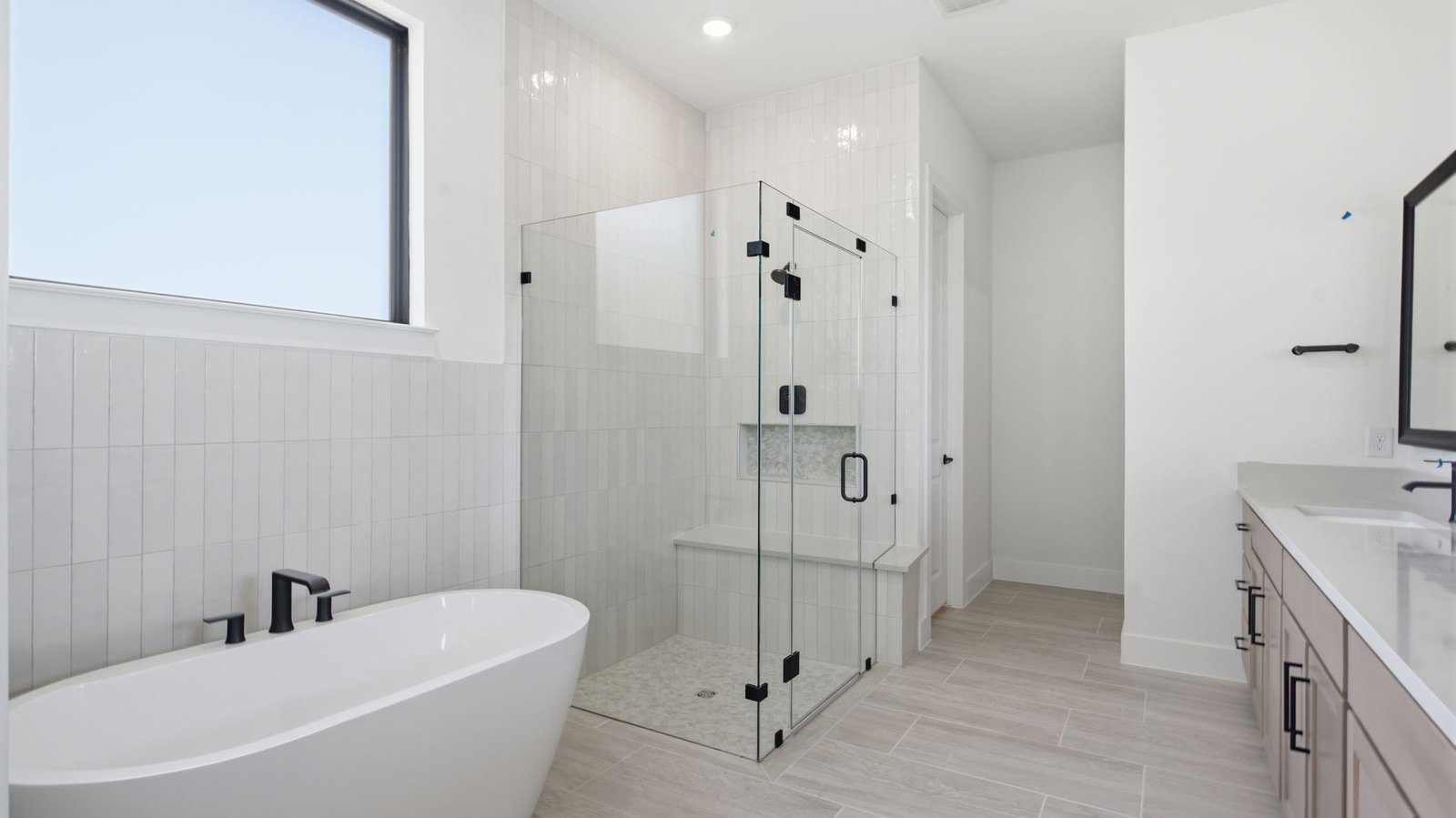 Luxurious primary bathroom with dual vanities, a soaking tub, and separate glass-enclosed walk in shower