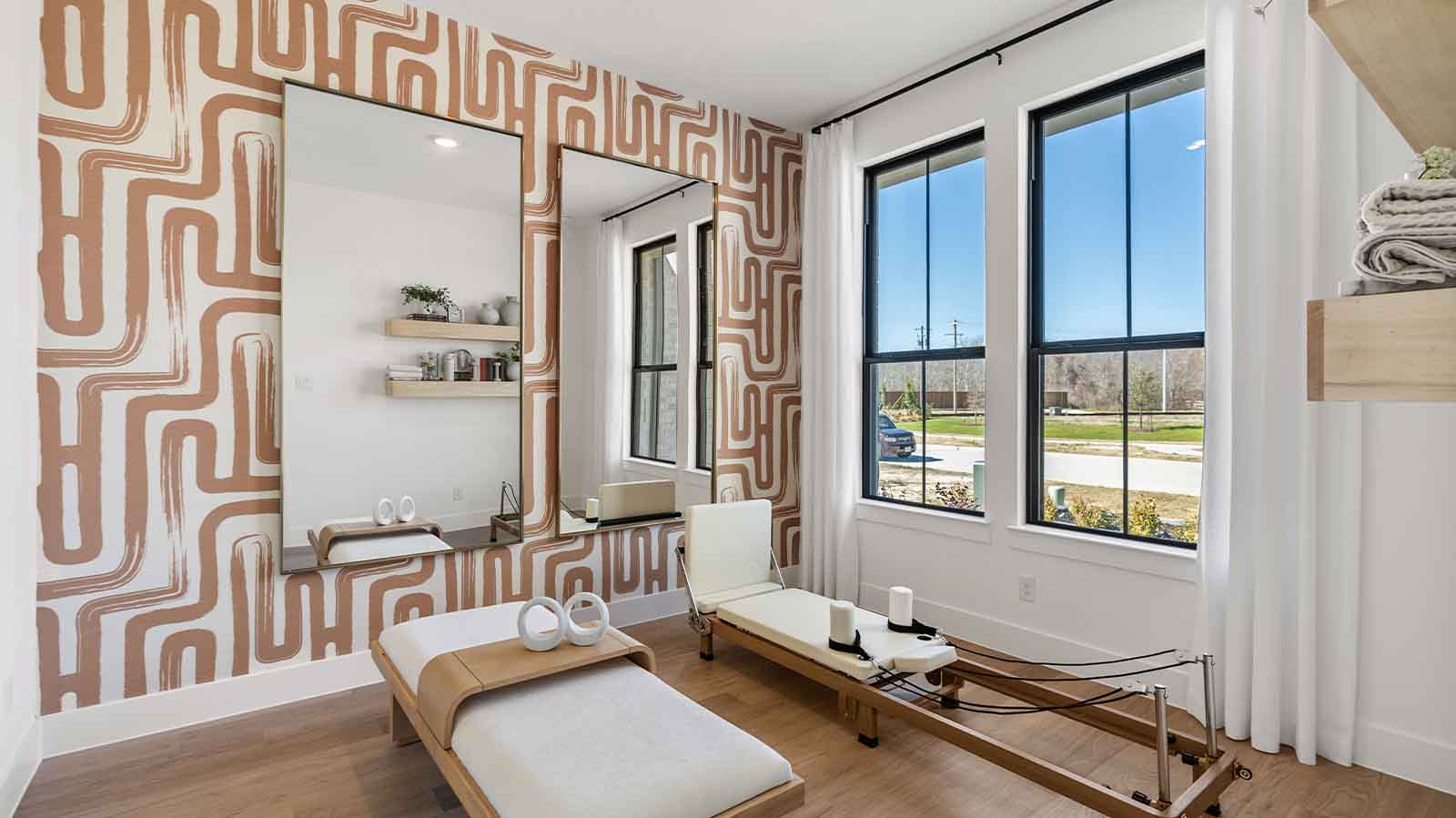 A bedroom shown as an at home gym with a bright window allowing natural light to enter.