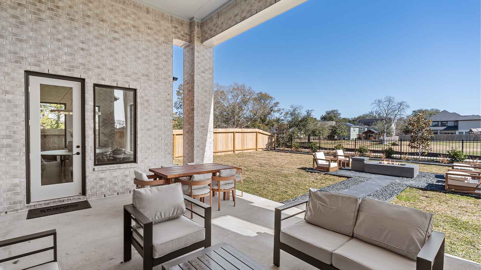 Outdoor covered patio with seating area overlooking a well-maintained lawn, perfect for relaxation.
