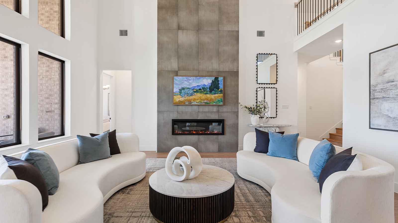 Elegant living room with soaring ceilings, a cozy electric fireplace, open-concept design, and seamless flow into a chef-inspired kitchen.