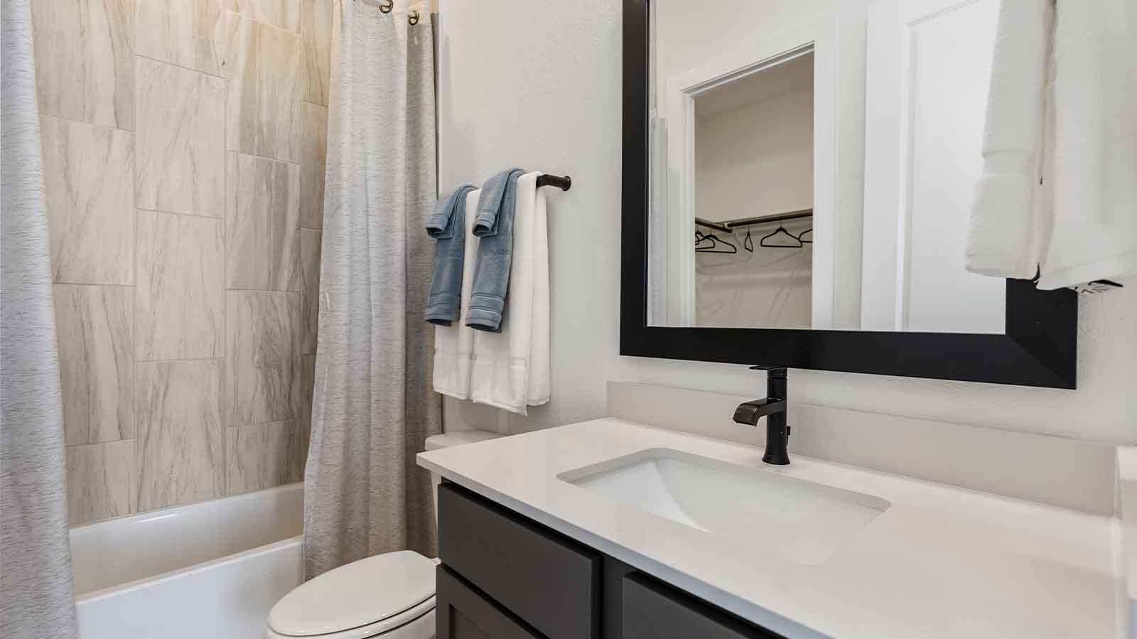 A secondary bathroom with a standing tub, one sink vanity, and a window for natural lighting
