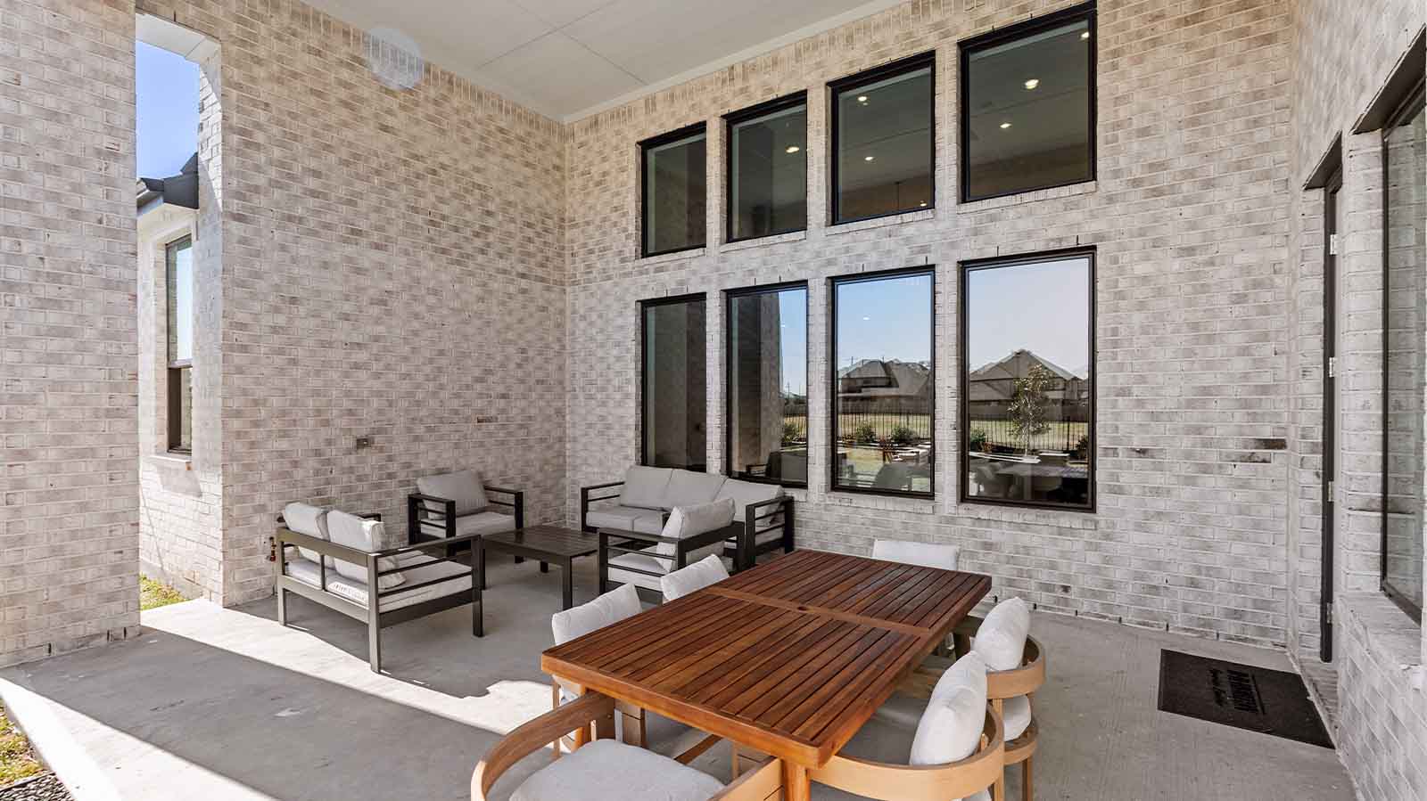 Outdoor covered patio with seating area overlooking a well-maintained lawn, perfect for relaxation.