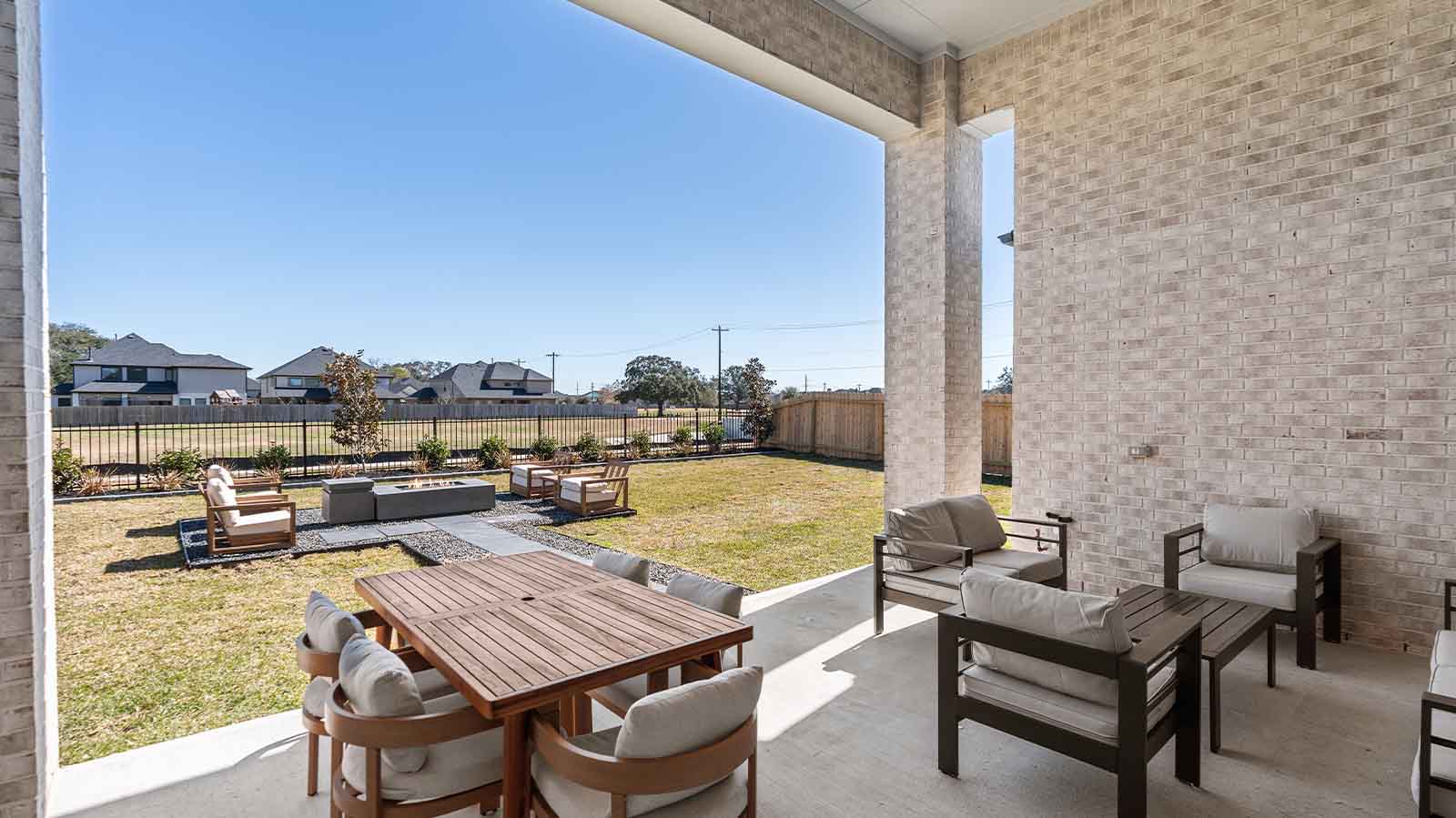Outdoor covered patio with seating area overlooking a well-maintained lawn, perfect for relaxation.