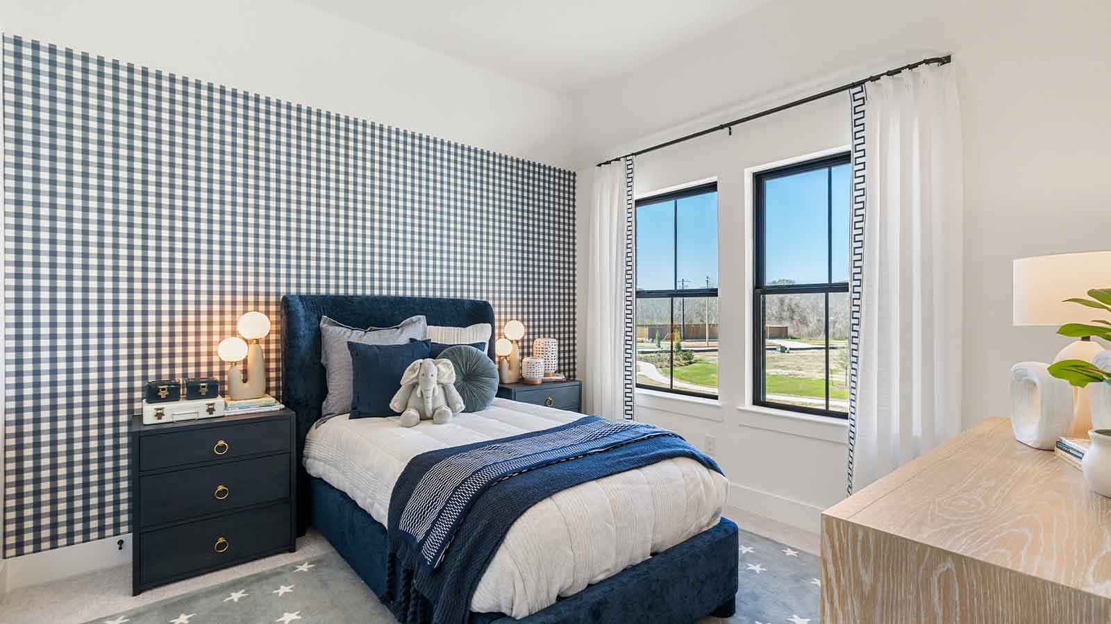 A third bedroom with two windows, decorated with bedroom furniture and wood flooring.