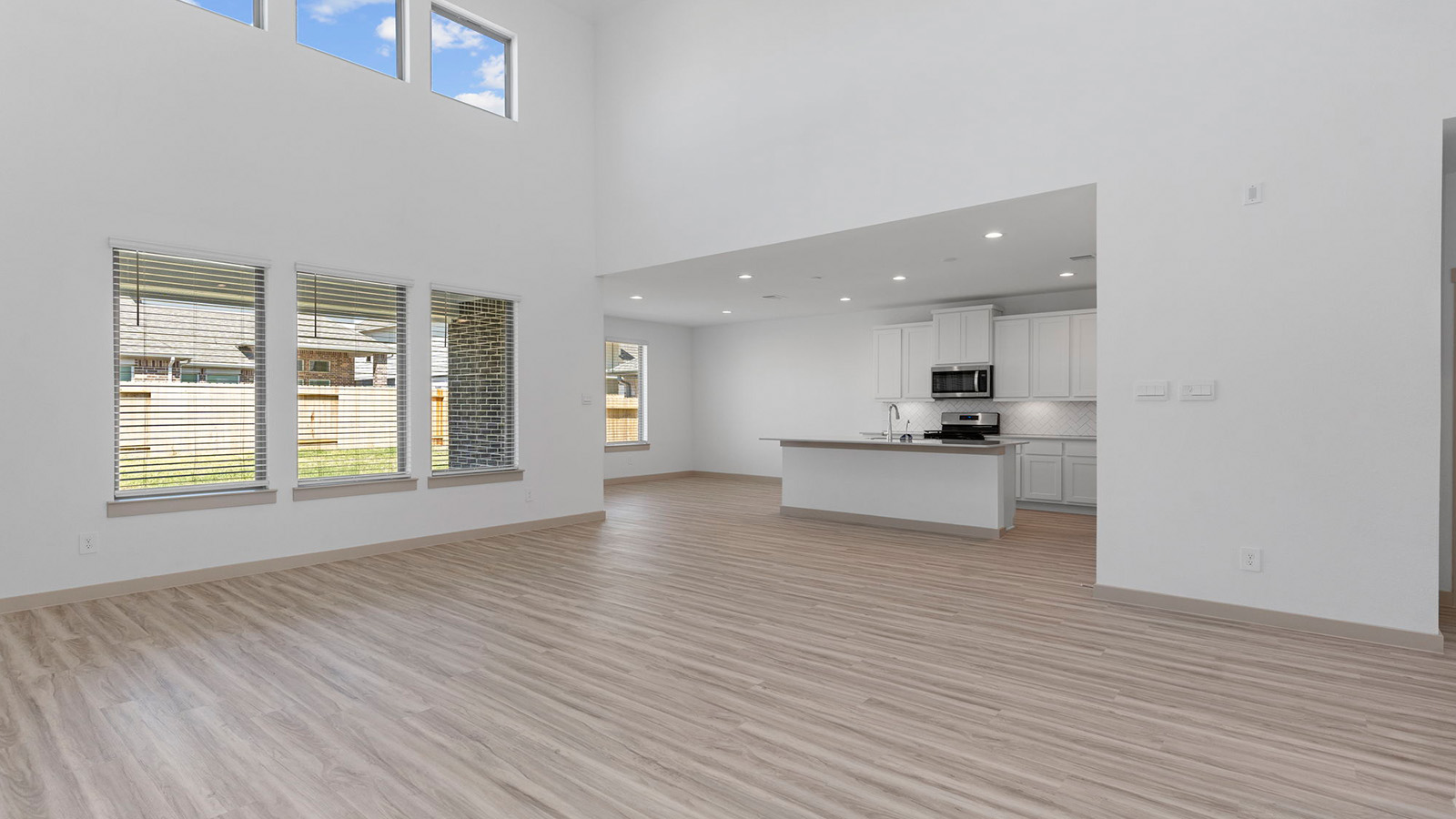 Open concept living room with high ceilings and four large windows
