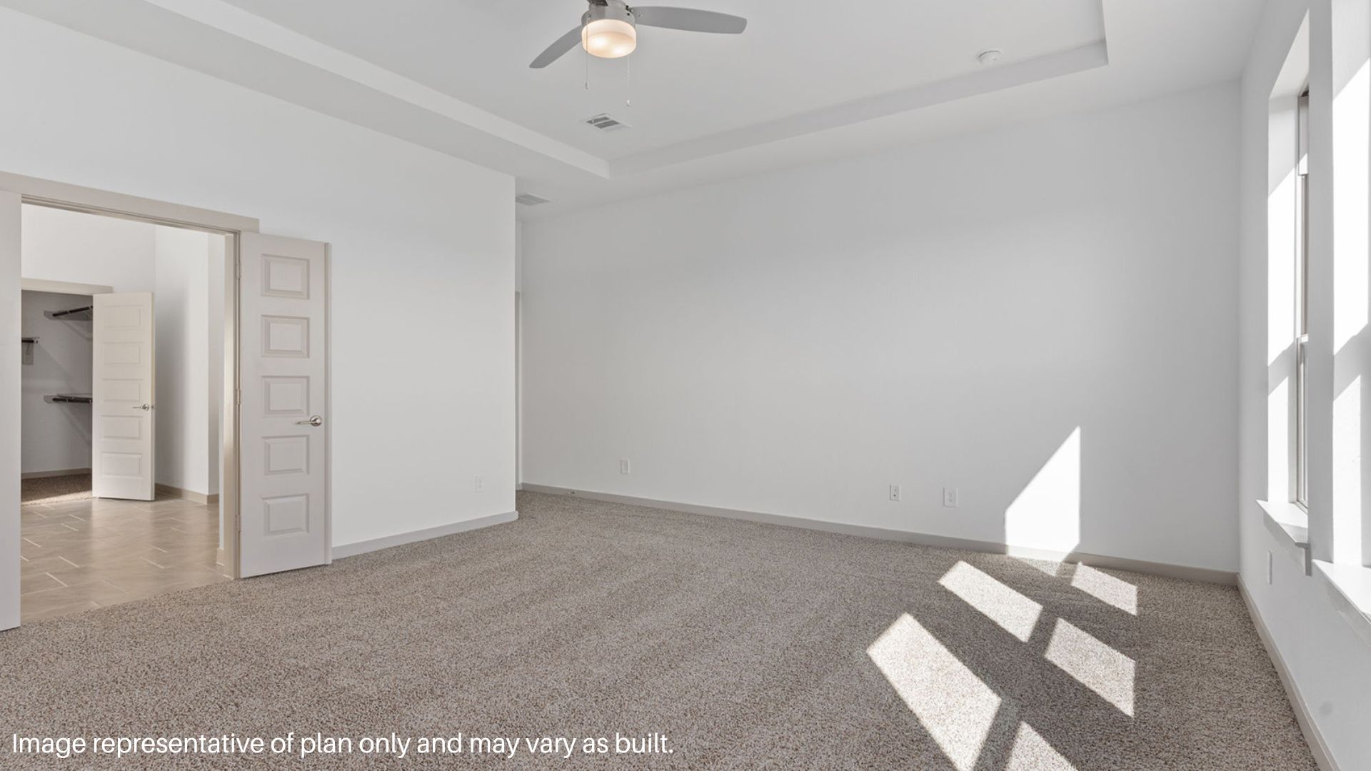 Spacious primary bedroom with carpet flooring and a ceiling fan.