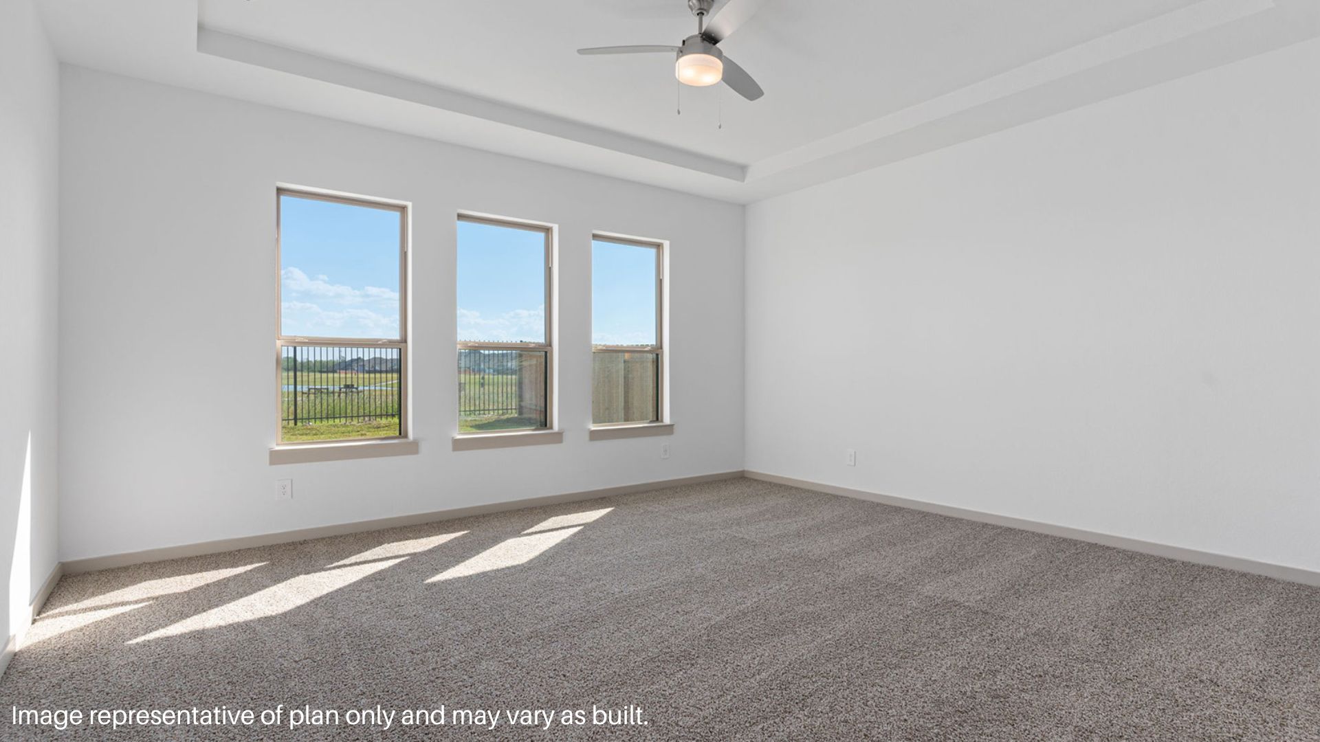 Spacious primary bedroom with carpet flooring and a ceiling fan.