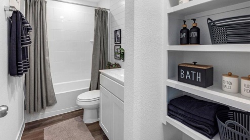 second bathroom with built in shelving and combo tub and shower