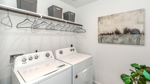 Laundry room with build in shelving and rod above the washer and dryer hook ups