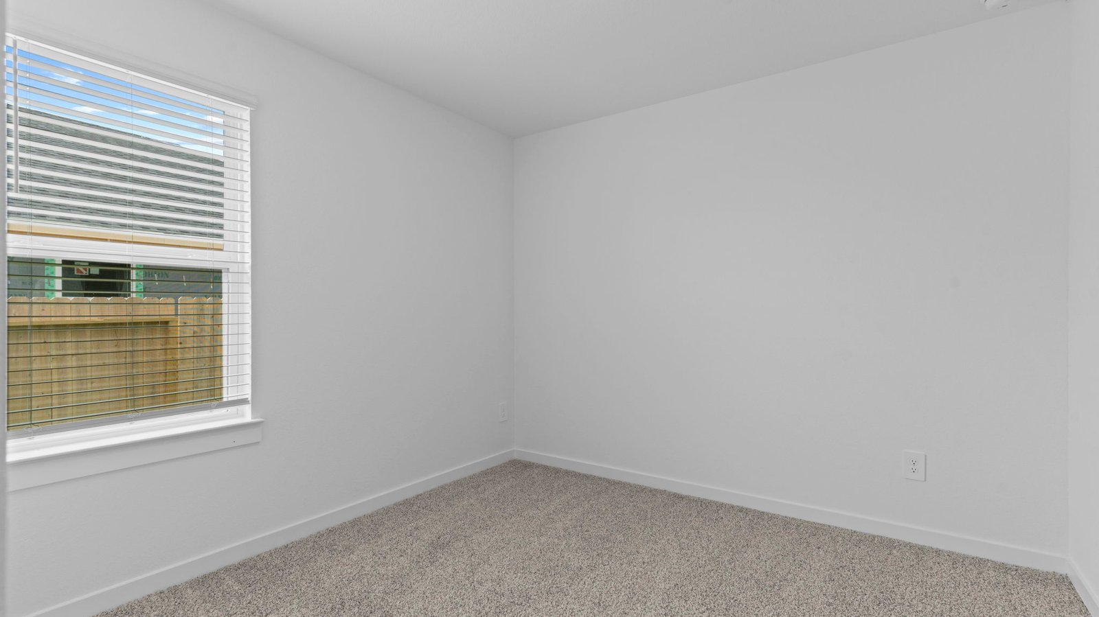 bedroom with beige carpet, white walls and a window
