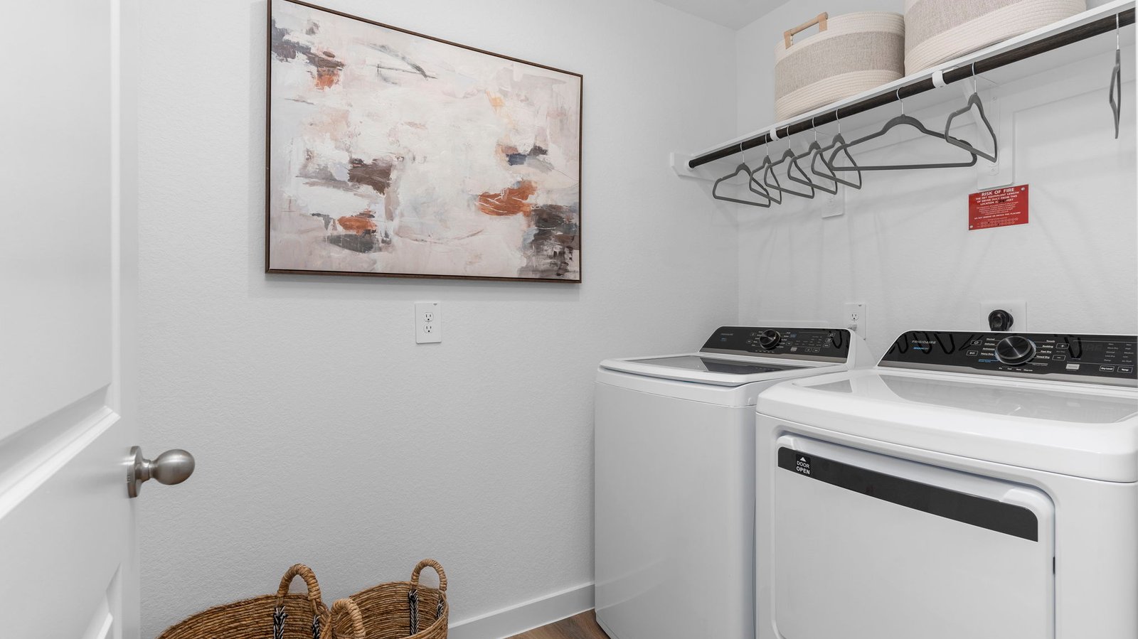 A laundry room featuring a washer and dryer, neatly arranged with ample space for laundry tasks and storage.
