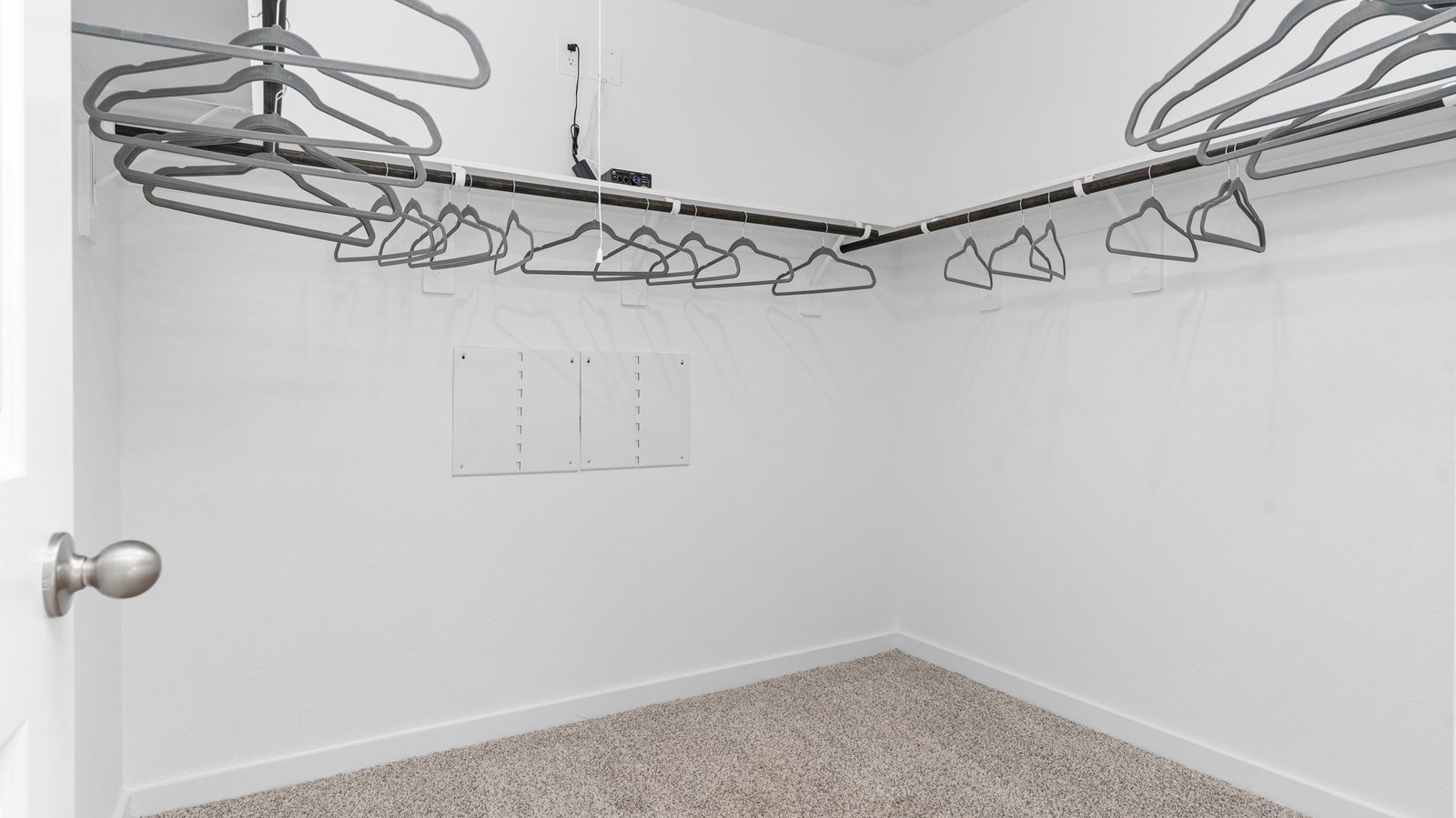 A spacious walk-in closet off the primary bathroom with multiple hanging rods, and shelves for maximum storage capabilities.