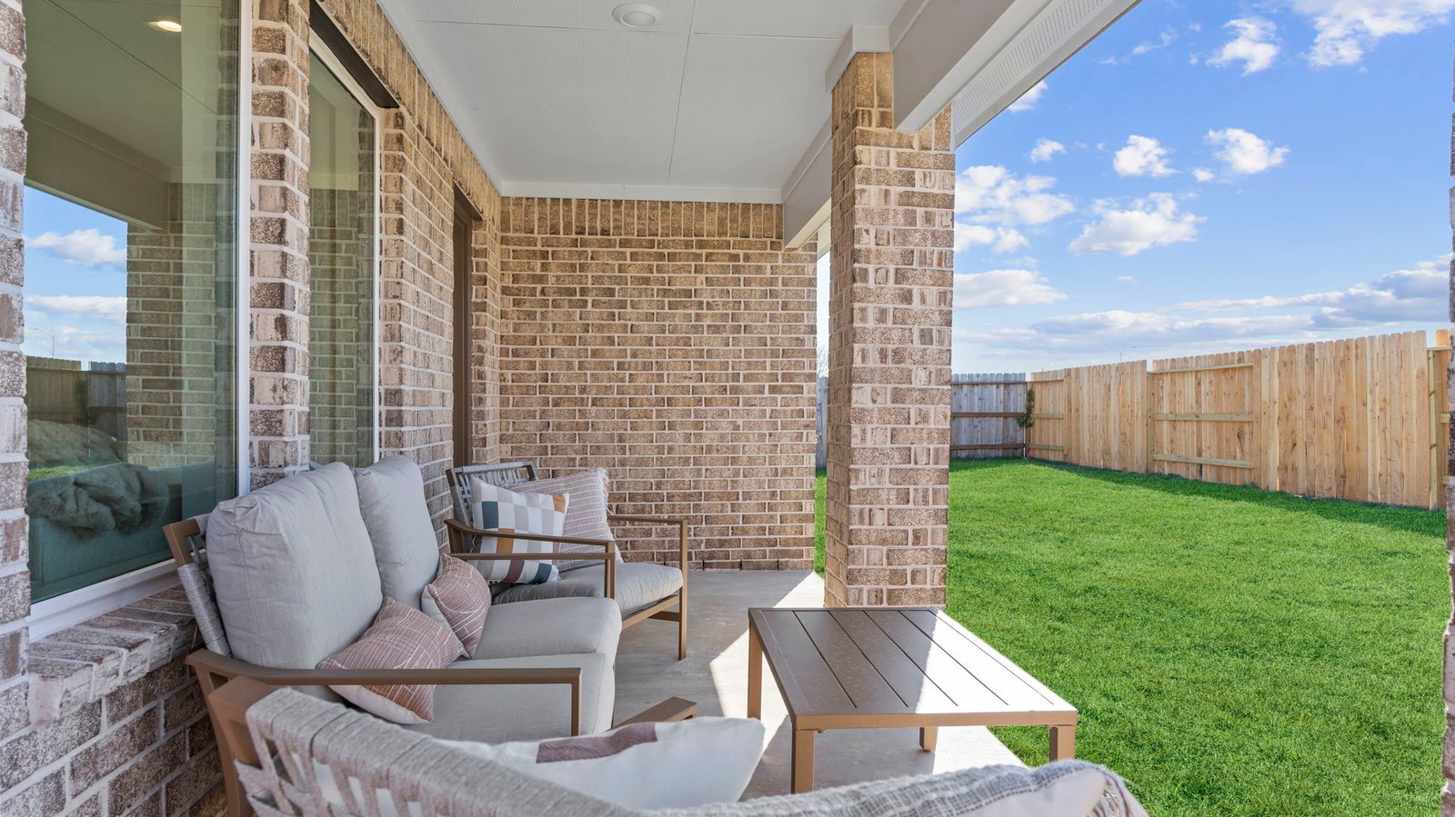 Outdoor covered patio with seating area overlooking a well-maintained lawn, perfect for relaxation.