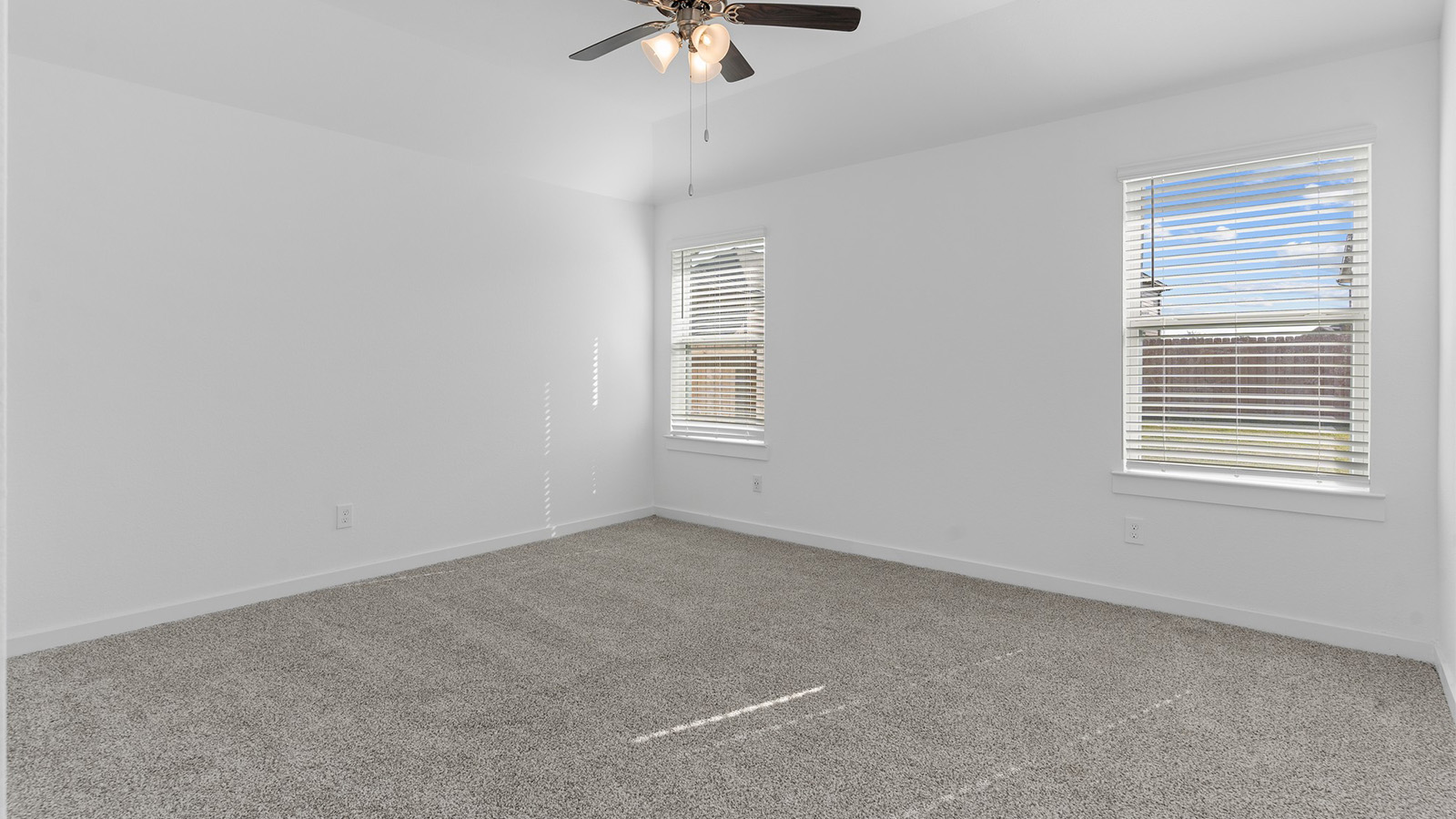 Primary bedroom with two large windows and celing fan