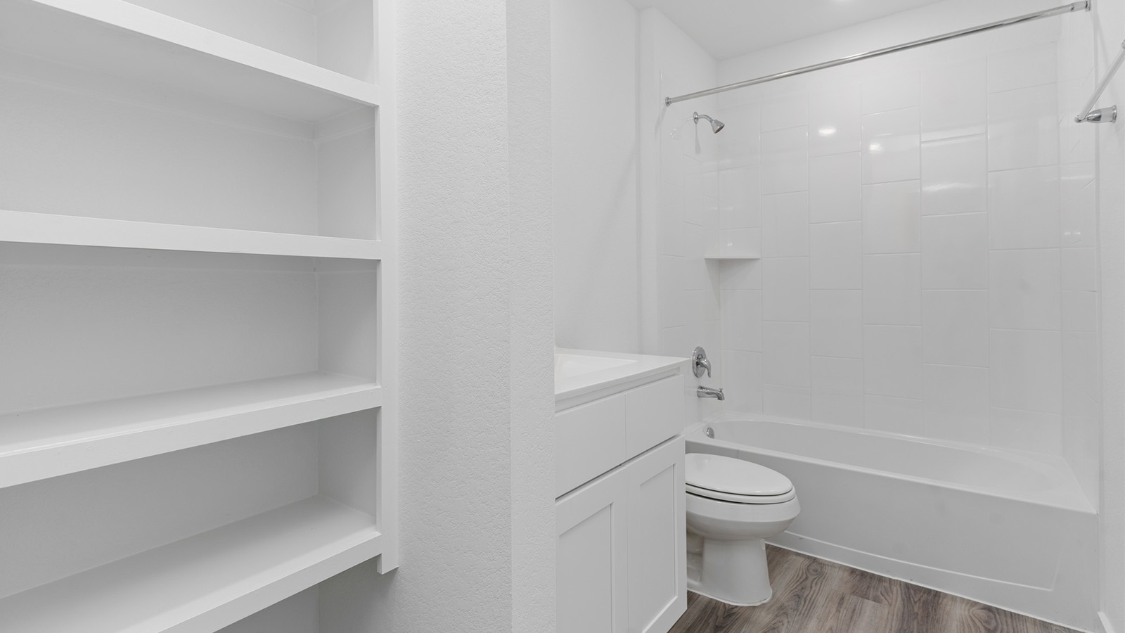 Secondary bathroom with open shelving and bathtub shower combo