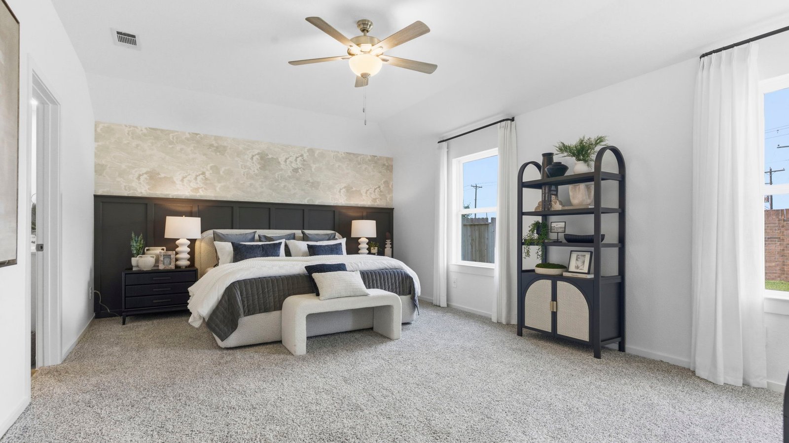 Primary bedroom with ceiling fan, plush carpeting, and a large walk-in closet.