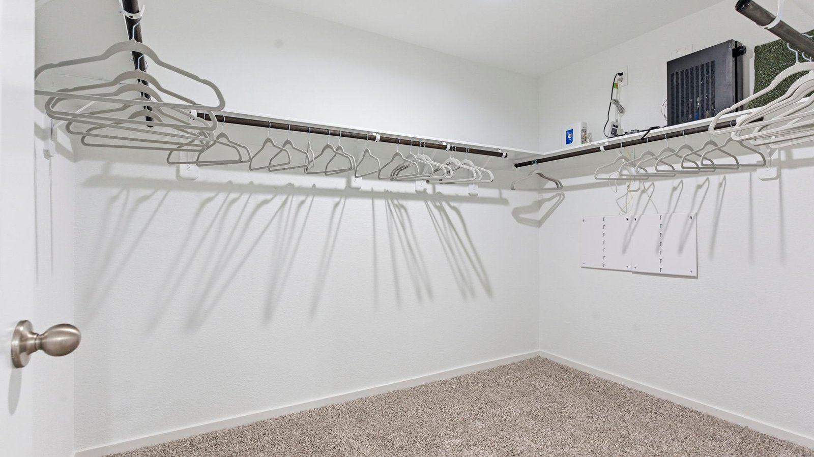 A spacious walk-in closet off the primary bathroom with multiple hanging rods, and shelves for maximum storage capabilities.