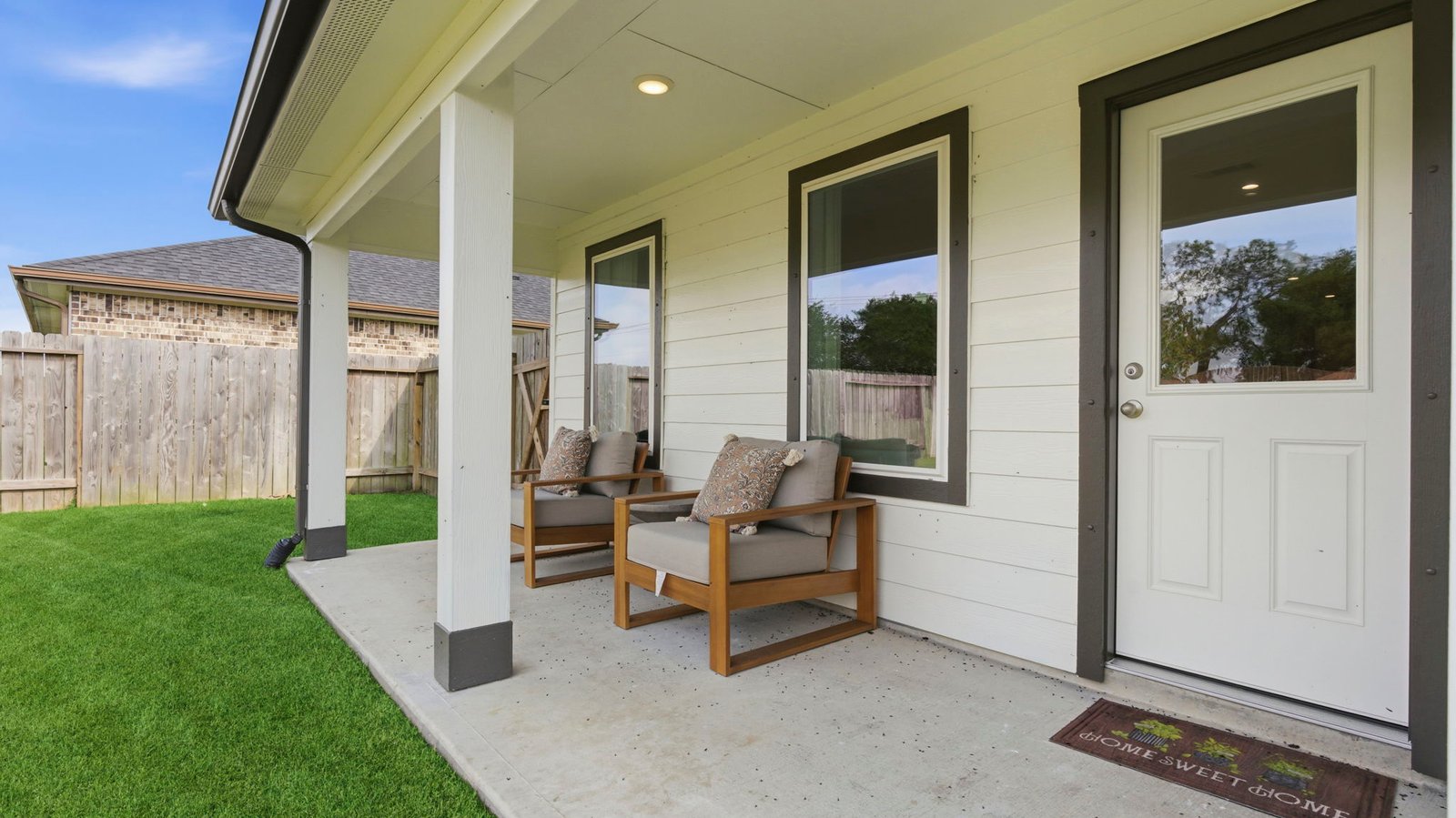 Outdoor covered patio with seating area overlooking a well-maintained lawn, perfect for relaxation.