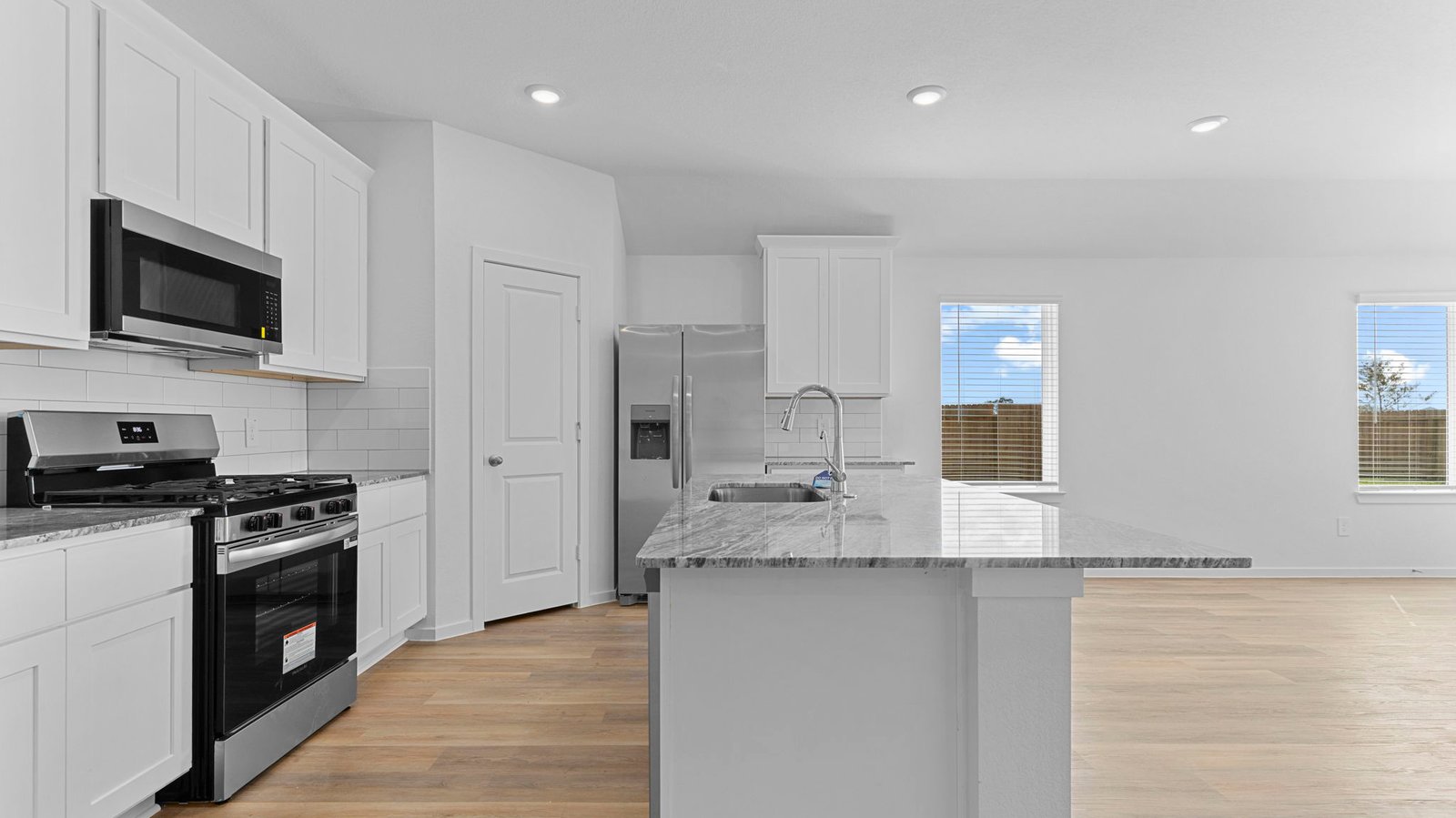 Bright and spacious kitchen with quartz countertops, stainless steel appliances, and an island with bar seating.
