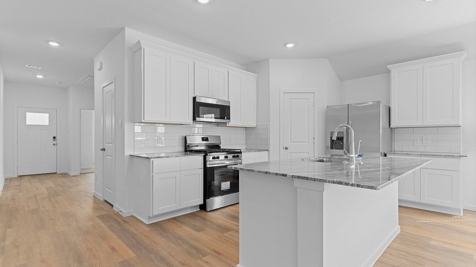 Bright and spacious kitchen with quartz countertops, stainless steel appliances, and an island with bar seating.