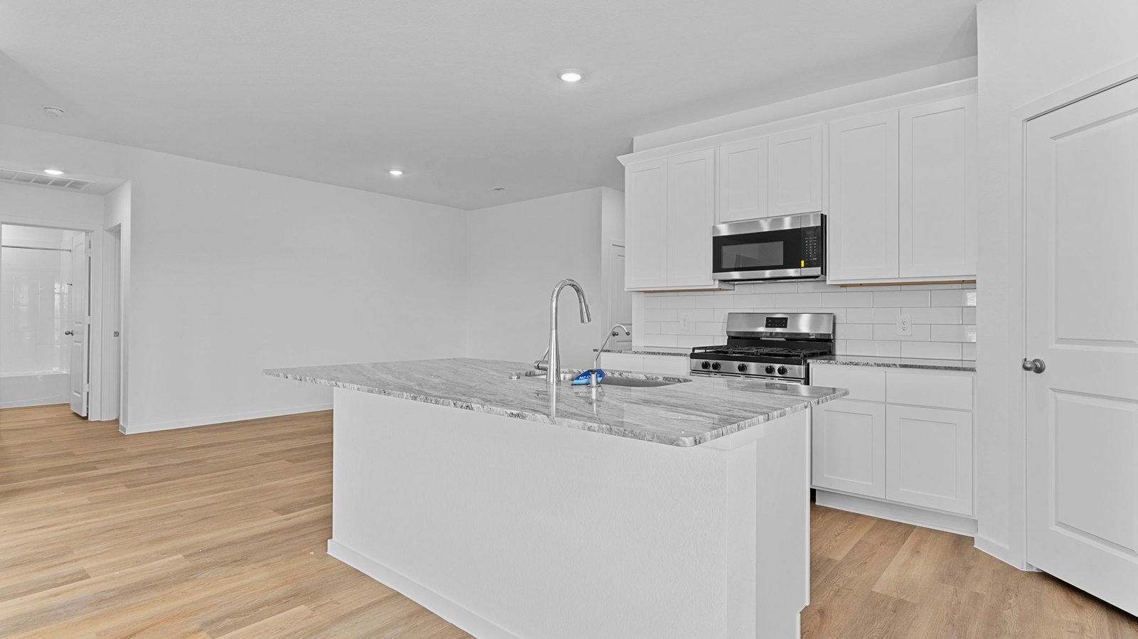An open concept kitchen with an island with bar seating and access to the living and dining areas.