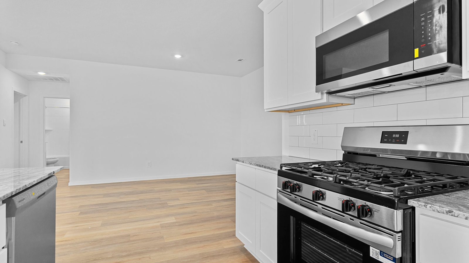Bright and spacious kitchen with quartz countertops, stainless steel appliances, and an island with bar seating.