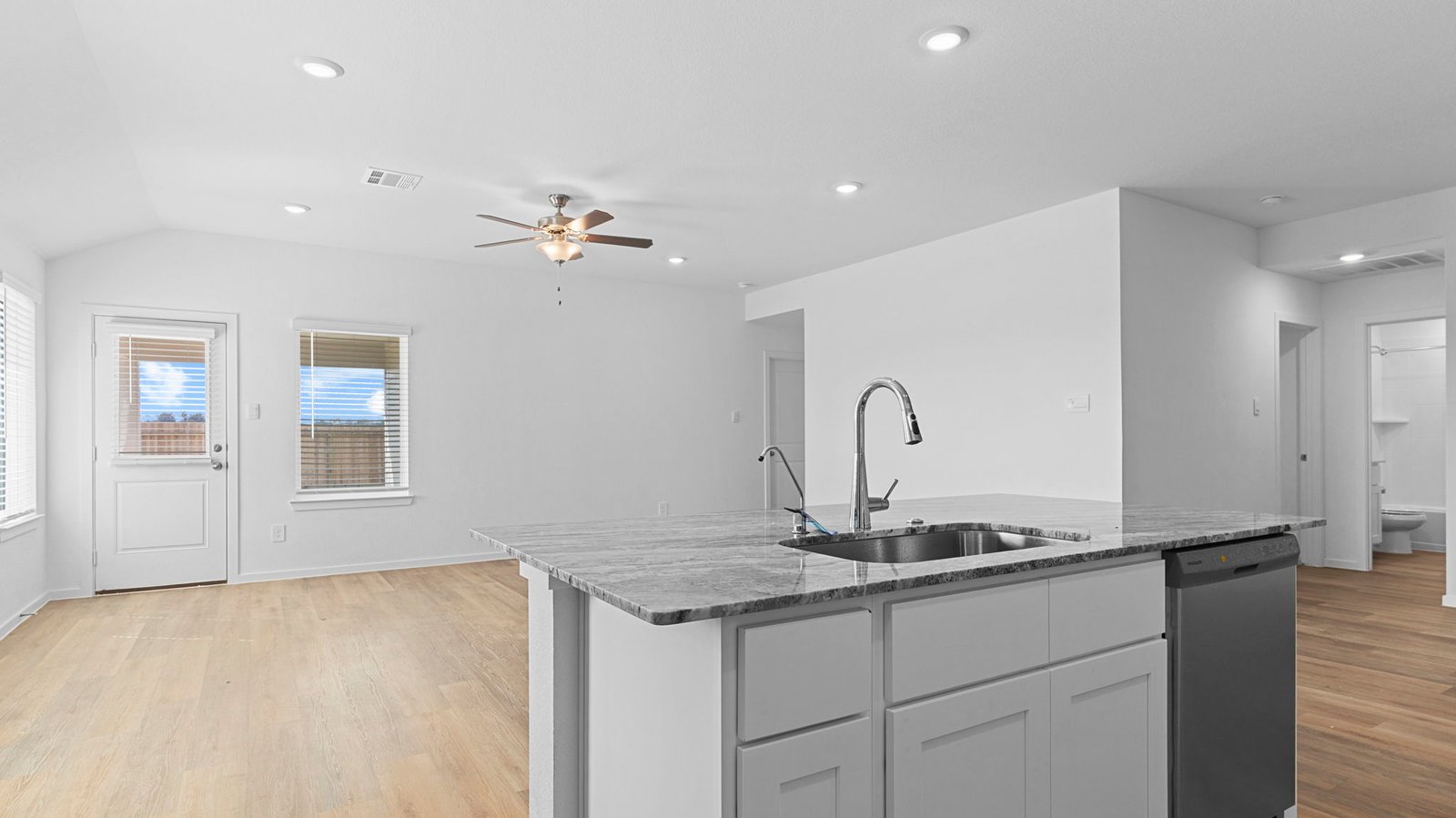 An open concept kitchen with an island with bar seating and access to the living and dining areas.