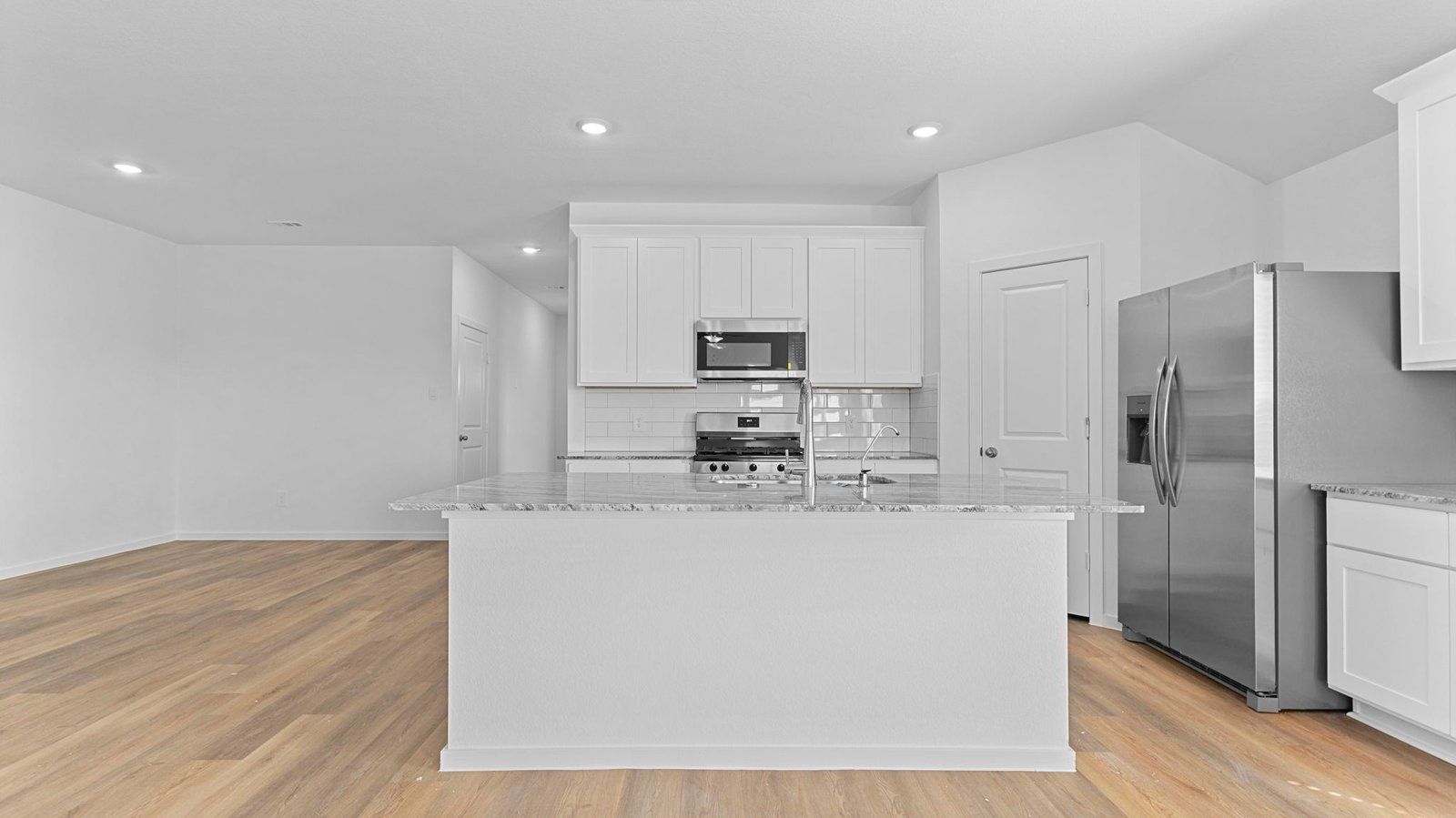 An open concept kitchen with an island with bar seating and access to the living and dining areas.