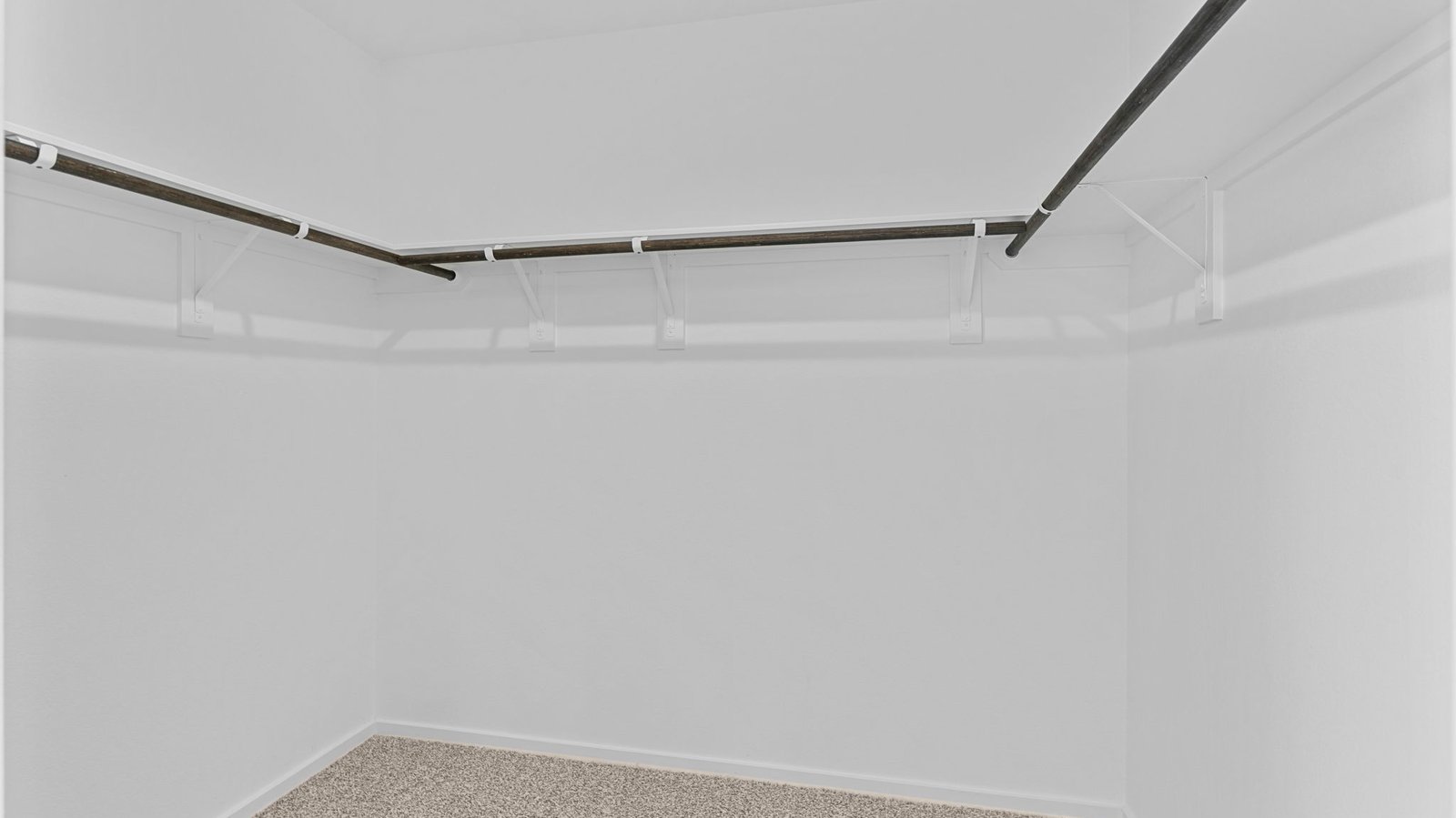 A spacious walk-in closet off the primary bathroom with multiple hanging rods, and shelves for maximum storage capabilities.