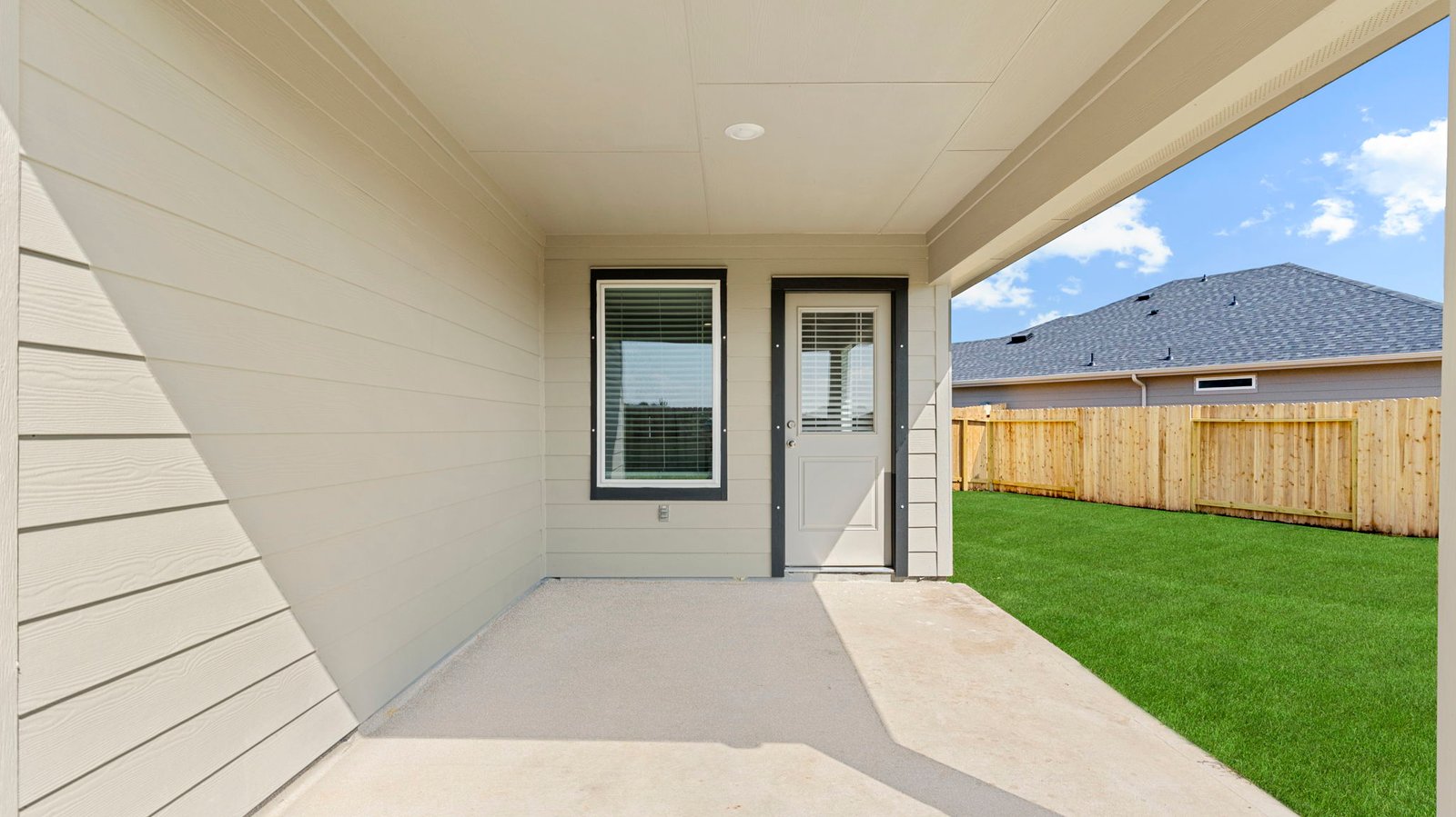 Outdoor covered patio with seating area overlooking a well-maintained lawn, perfect for relaxation.