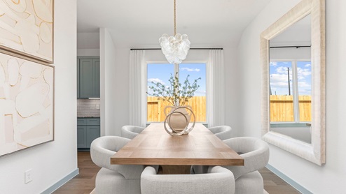 The dining room with hardwood floors, hanging bright light fixture centered above the table, with a large window for natural lighting.