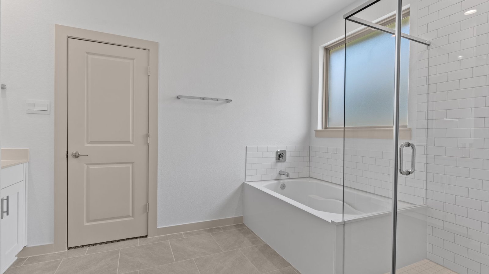 Master bath has  garden tub with white subway tile, an opaque window and a white subway tile walk-in shower with a glass door.