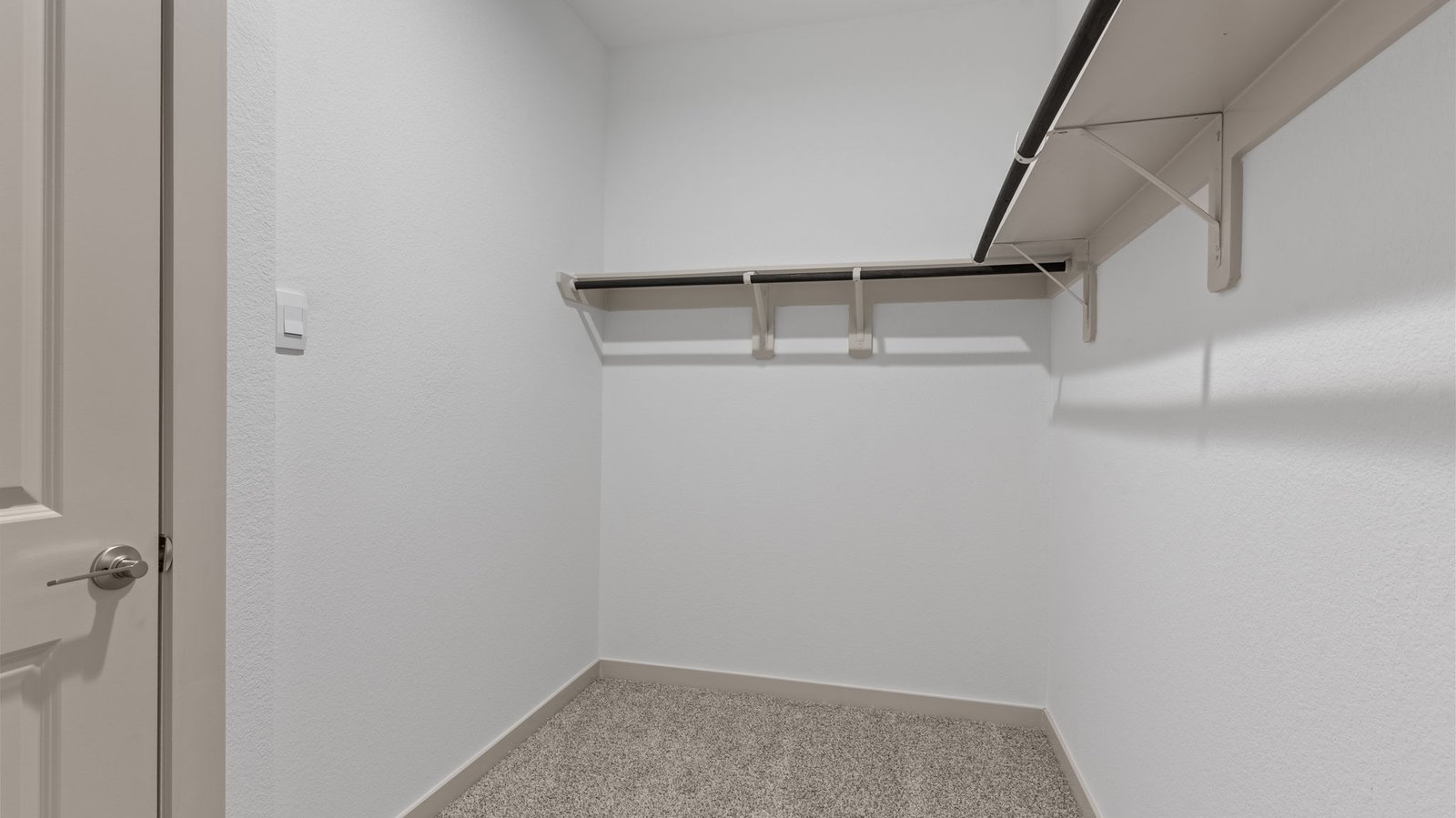 Master bedroom walk-in closet with neutral carpet.