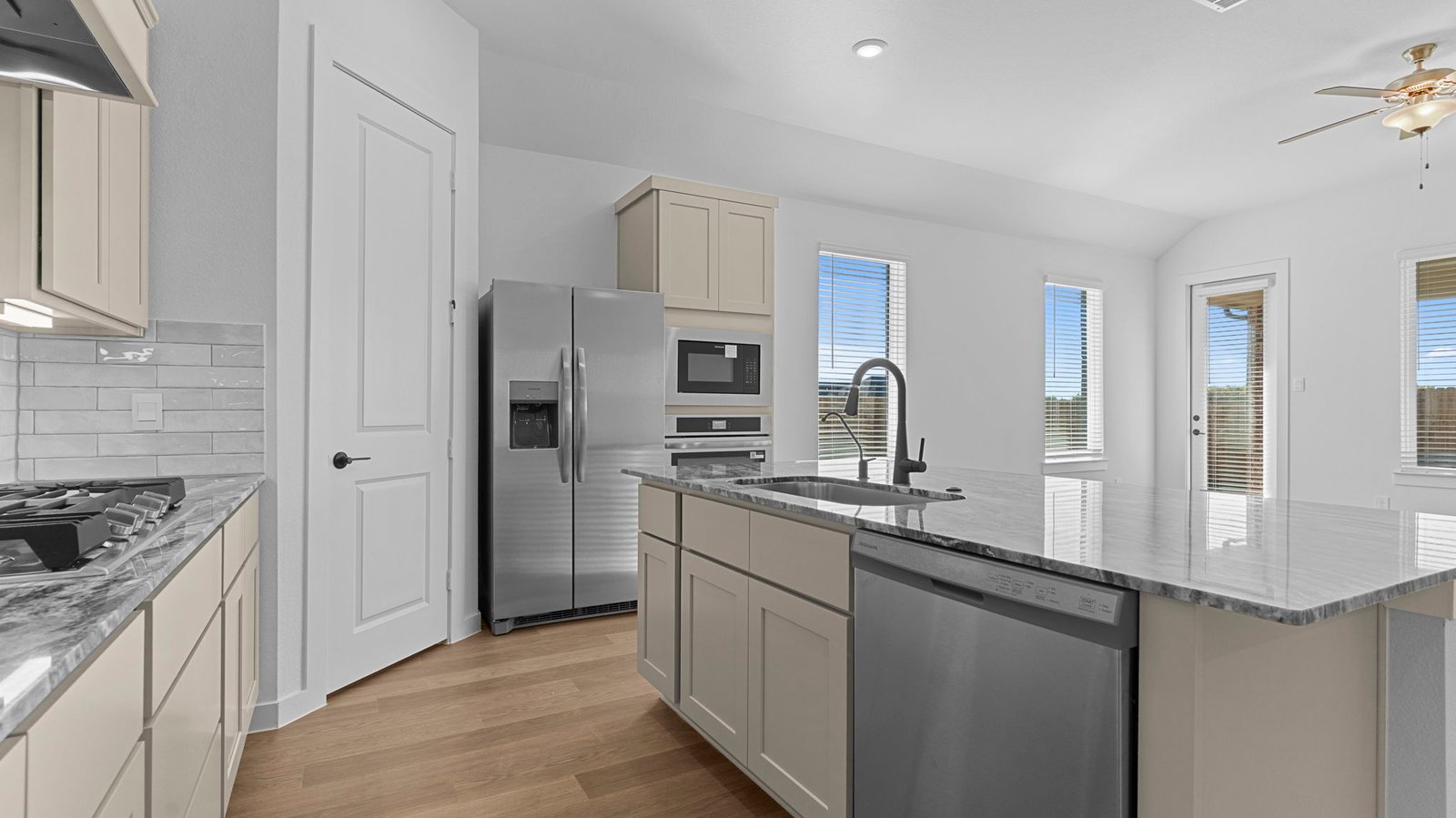 Bright and spacious kitchen with quartz countertops, stainless steel appliances, and an island with bar seating.