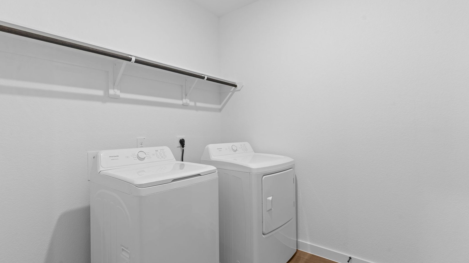A laundry room featuring a washer and dryer, neatly arranged with ample space for laundry tasks and storage.