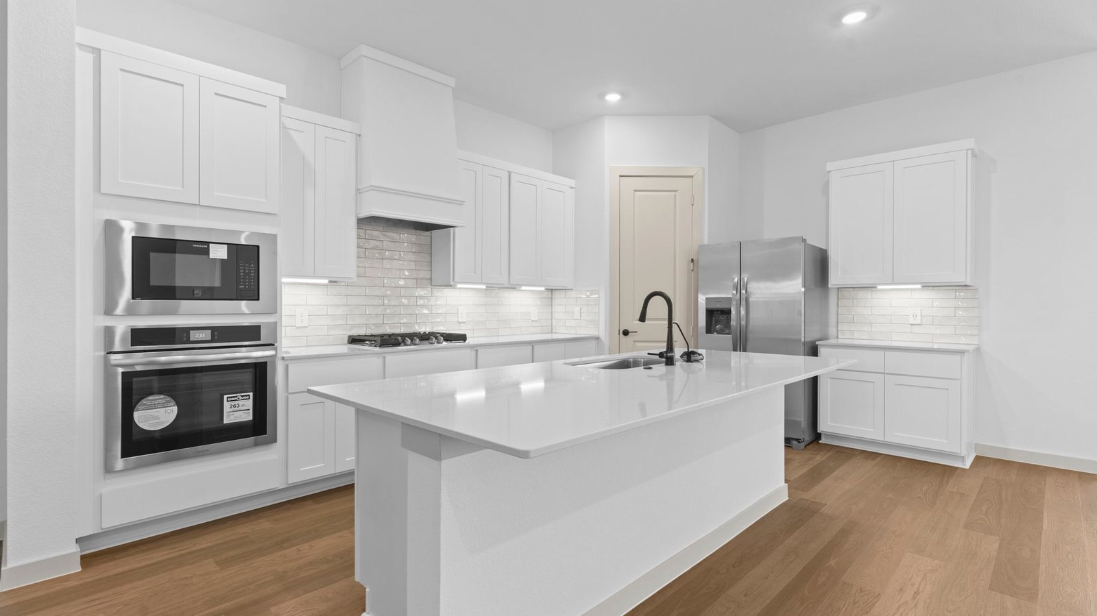 Bright and spacious kitchen with quartz countertops, stainless steel appliances, and an island with bar seating.
