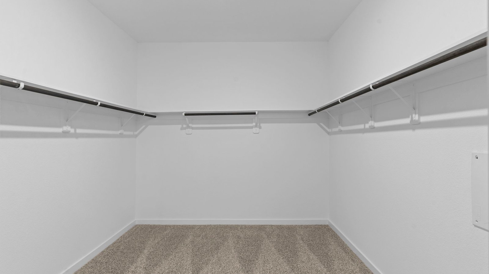 A spacious walk-in closet off the primary bathroom with multiple hanging rods, and shelves for maximum storage capabilities.