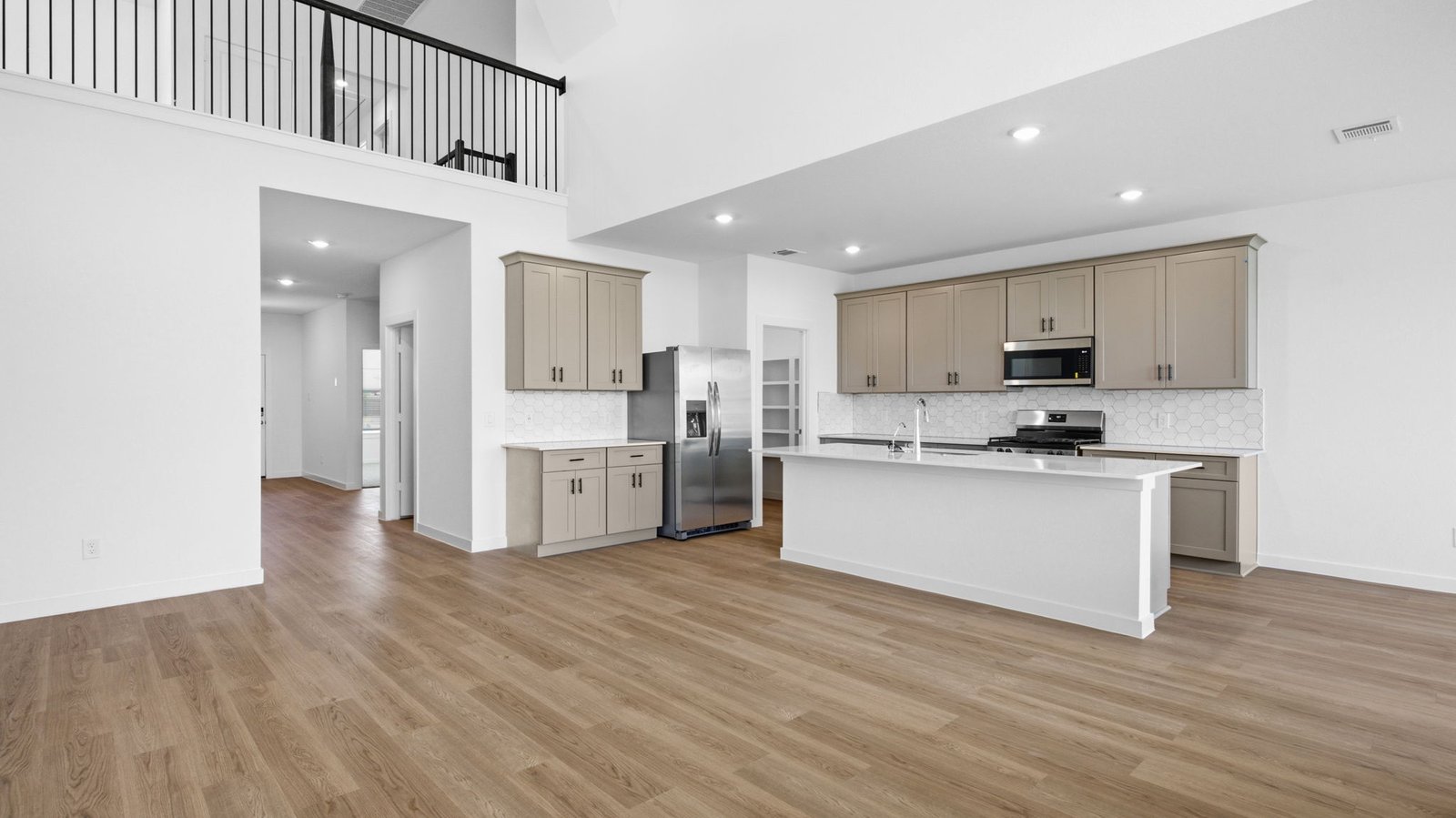 A luxurious living room featuring tall ceilings, large windows for natural lighting wood flooring and a view to the backyard.