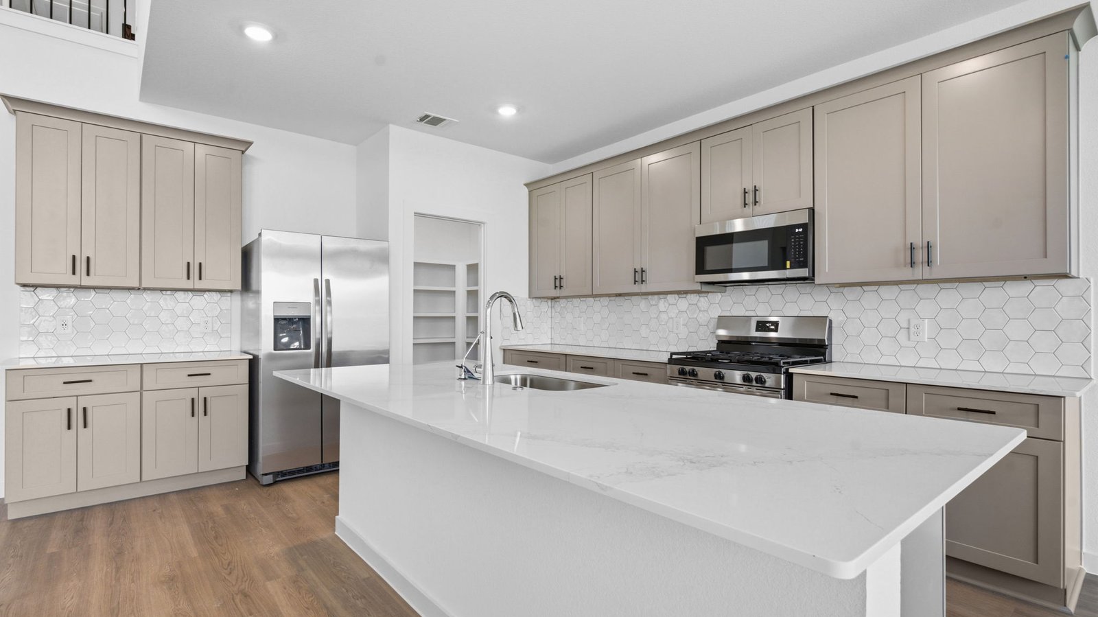 Bright and spacious kitchen with quartz countertops, stainless steel appliances, and an island with bar seating.