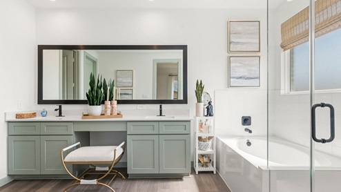 A modern bathroom featuring a double sink pale green vanity with white granite countertops and walk-in shower and separate garden tub.