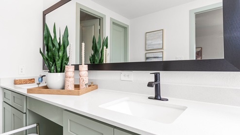 Primary bathroom featuring a double sink pale green vanity with white granite countertops.