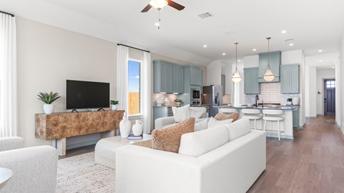 A spacious open floor plan living room and kitchen area with hardwood floors, and trey ceilings.