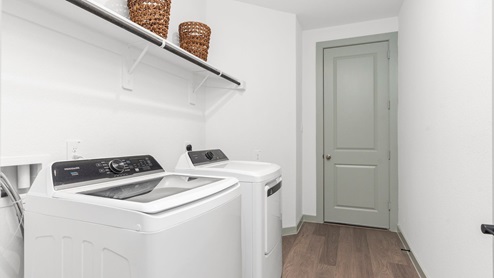 Spacious laundry area has room for a washer and dryer with built in shelves.