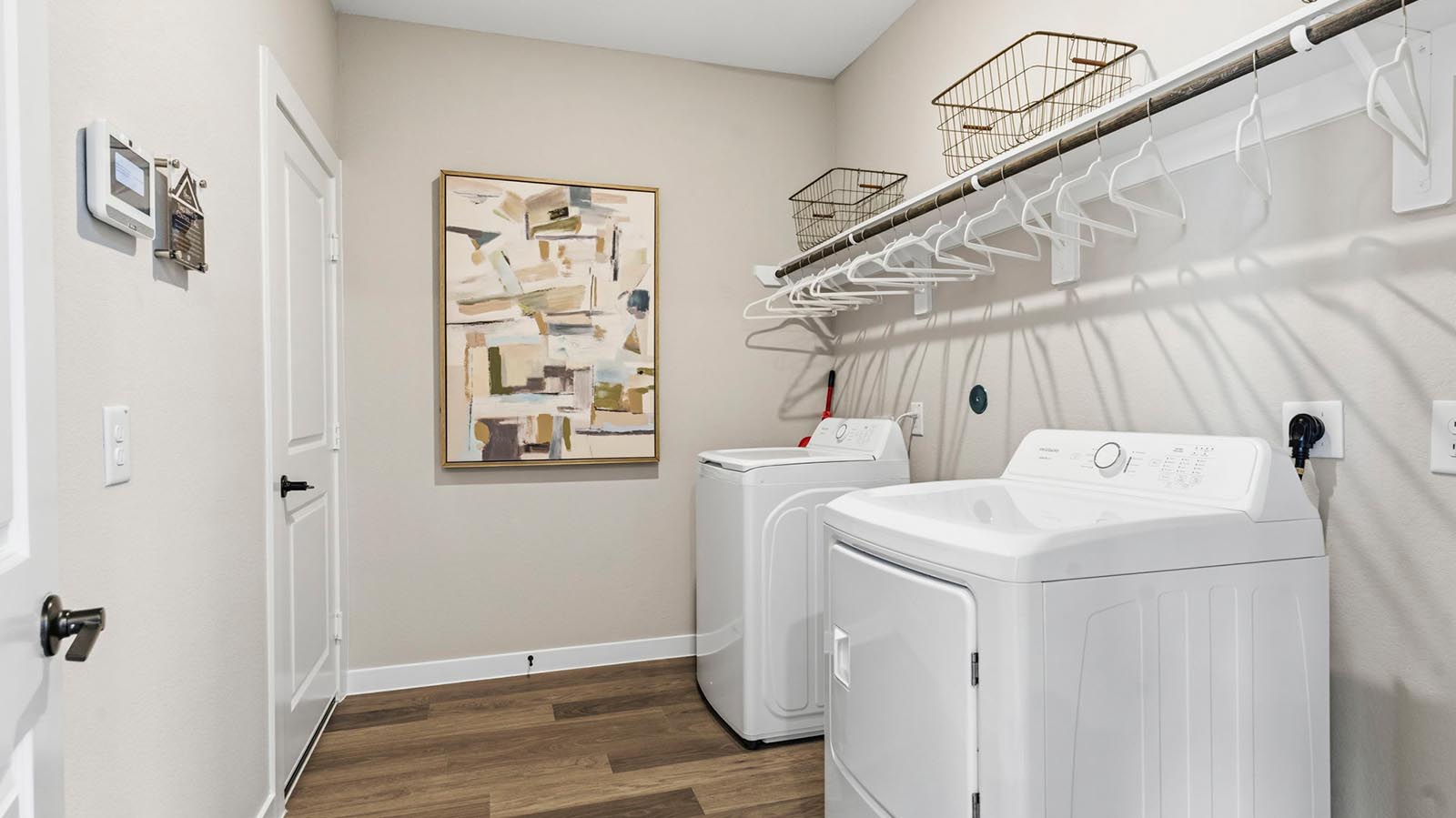 A laundry room featuring a washer and dryer, neatly arranged with ample space for laundry tasks and storage.