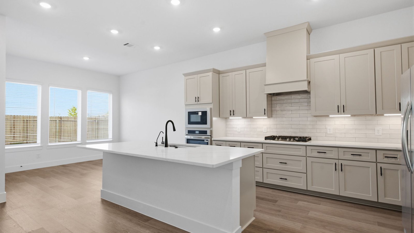 Bright and spacious kitchen with granite countertops, stainless steel appliances, and an island with bar seating.