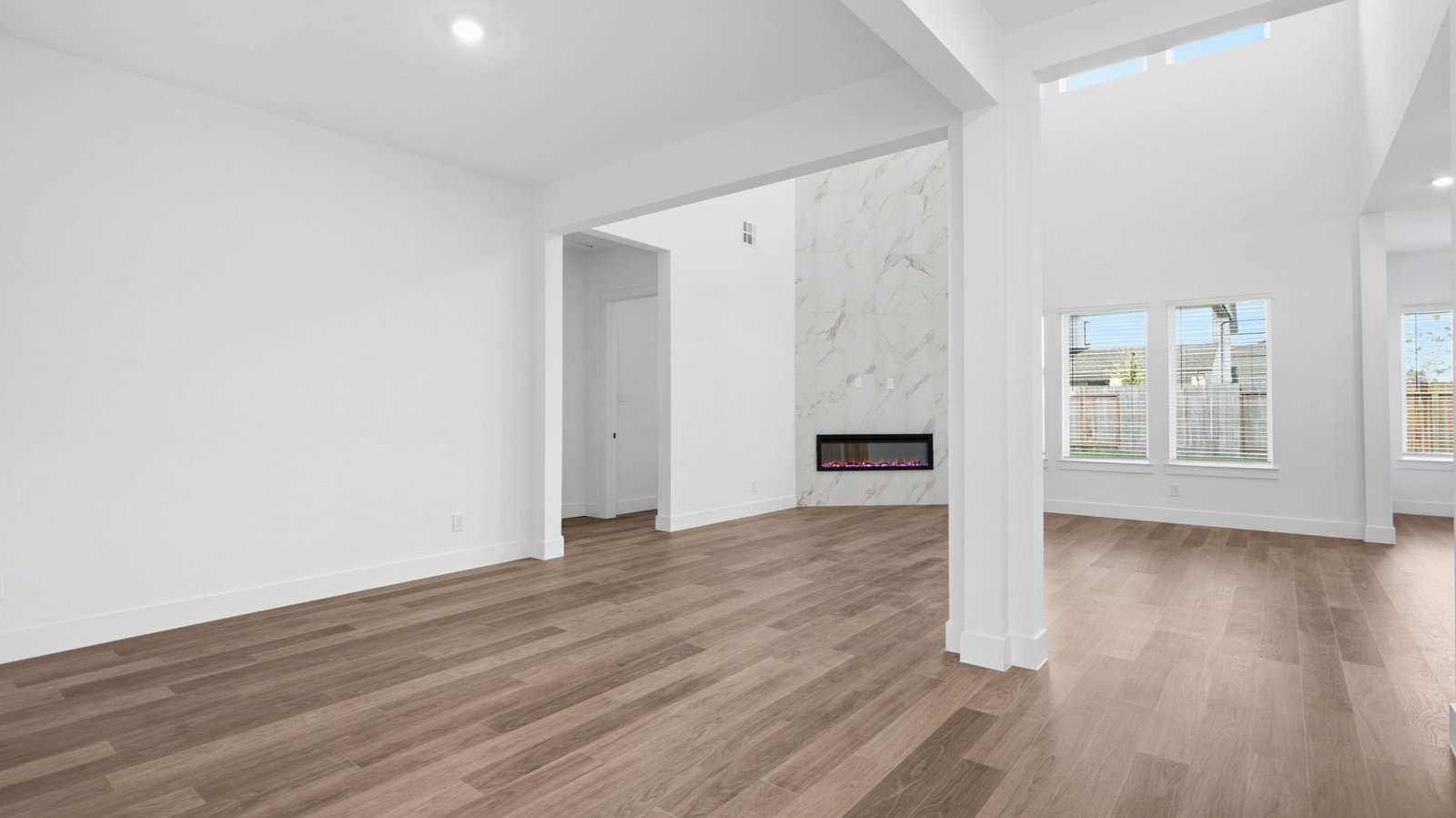 Spacious dining area with vinyl wood flooring, large window and a tall ceiling.