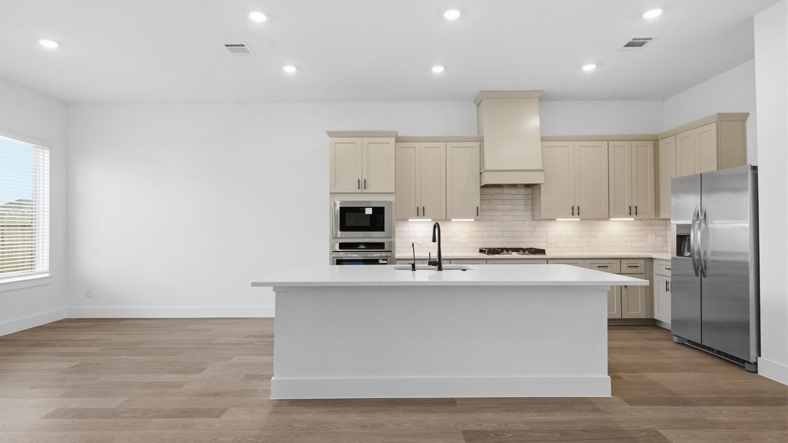 Bright and spacious kitchen with granite countertops, stainless steel appliances, and an island with bar seating.