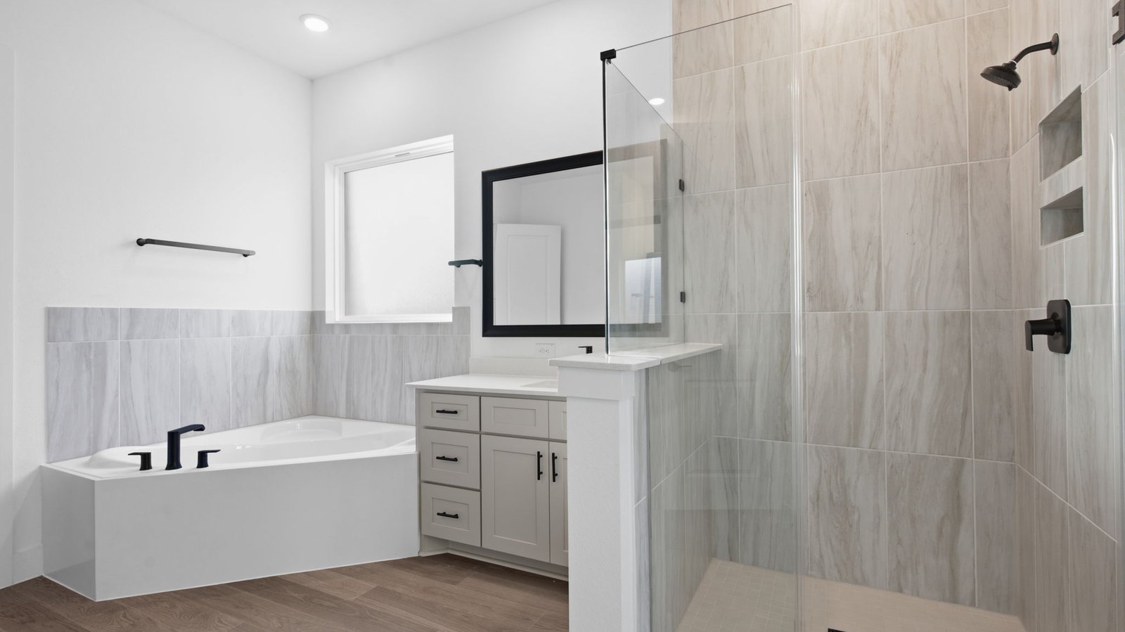 Luxurious primary bathroom with dual vanities, a soaking tub, glass-enclosed shower and walk-in closet.