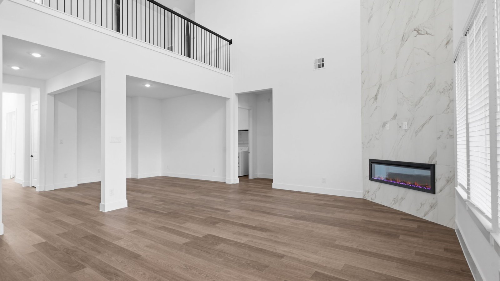 A luxurious living room featuring tall ceilings, large windows for natural lighting wood flooring and a view to the backyard.
